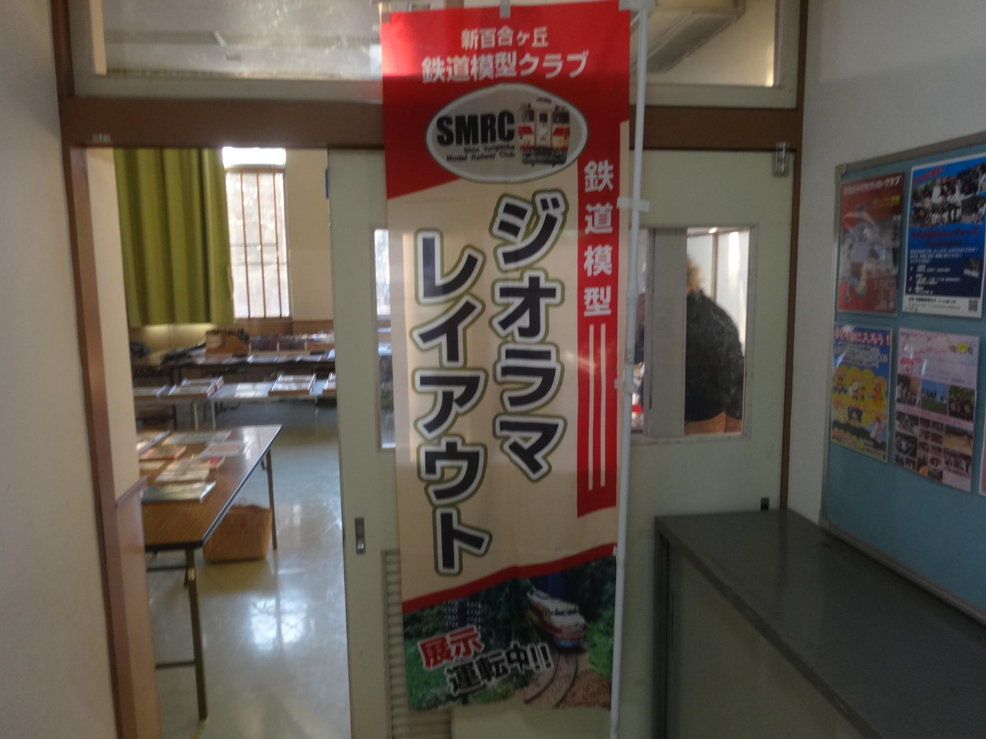 トレーニング室前に 新百合ヶ丘鉄道クラブ の旗が立てられている写真