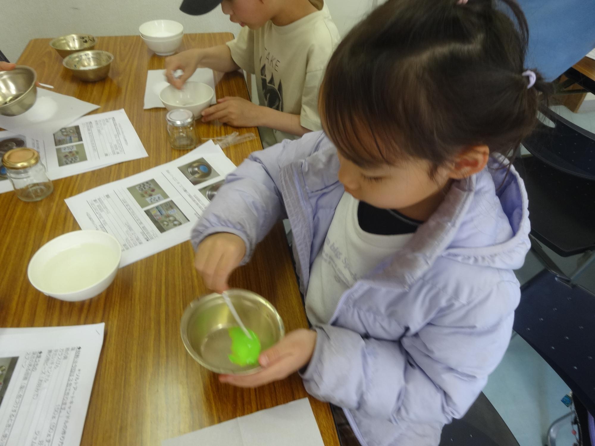 塩に水彩絵の具で色をつけ、なじませている小学生の写真