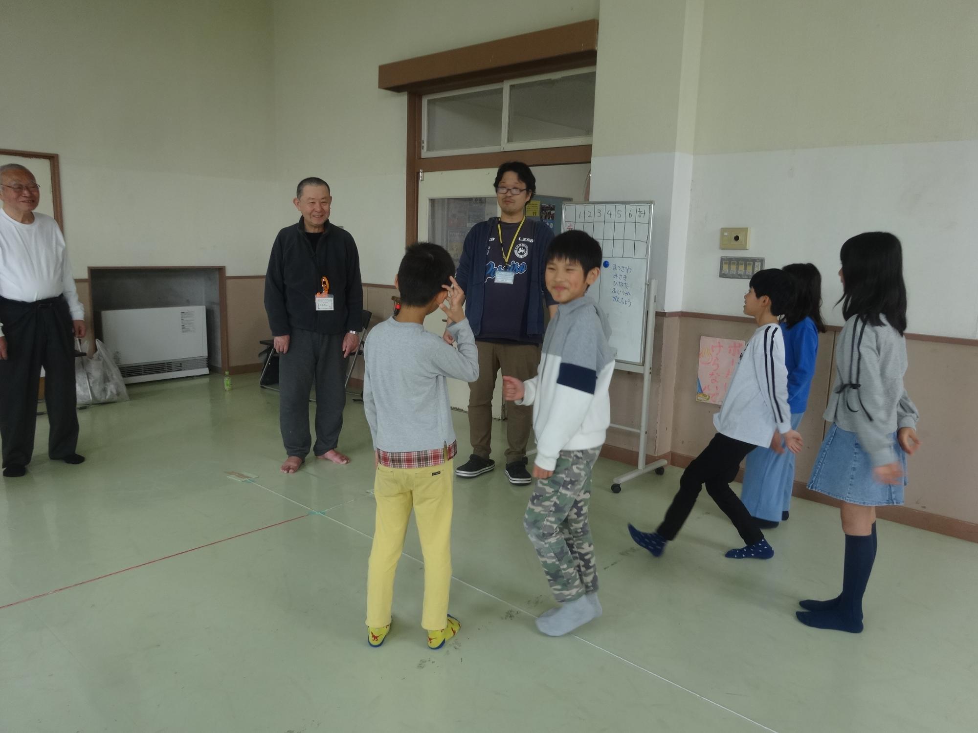ボッチャを始める前に、小学生とボッチャの先生、高齢の参加者の方とで挨拶をしている写真