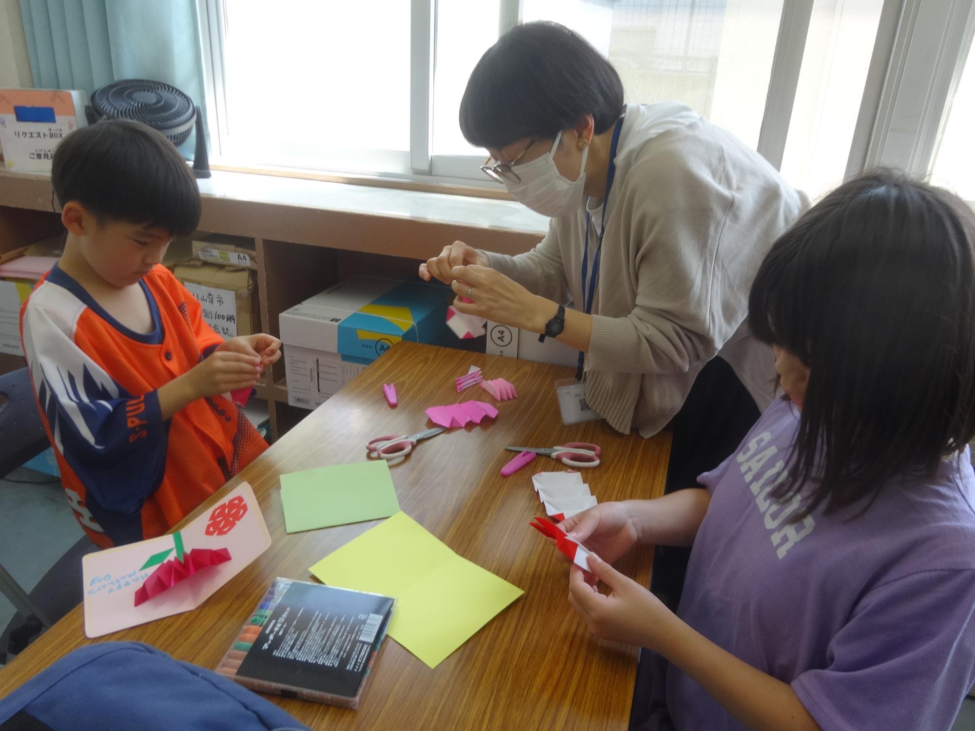 カーネーションの形のポップアップカードを作る二人の小学生