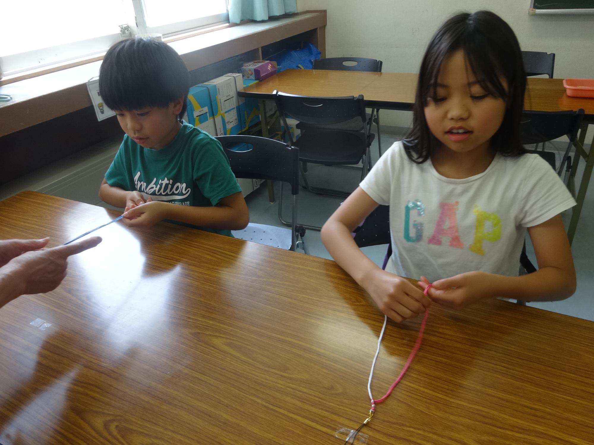 ストラップを編む二人の小学生