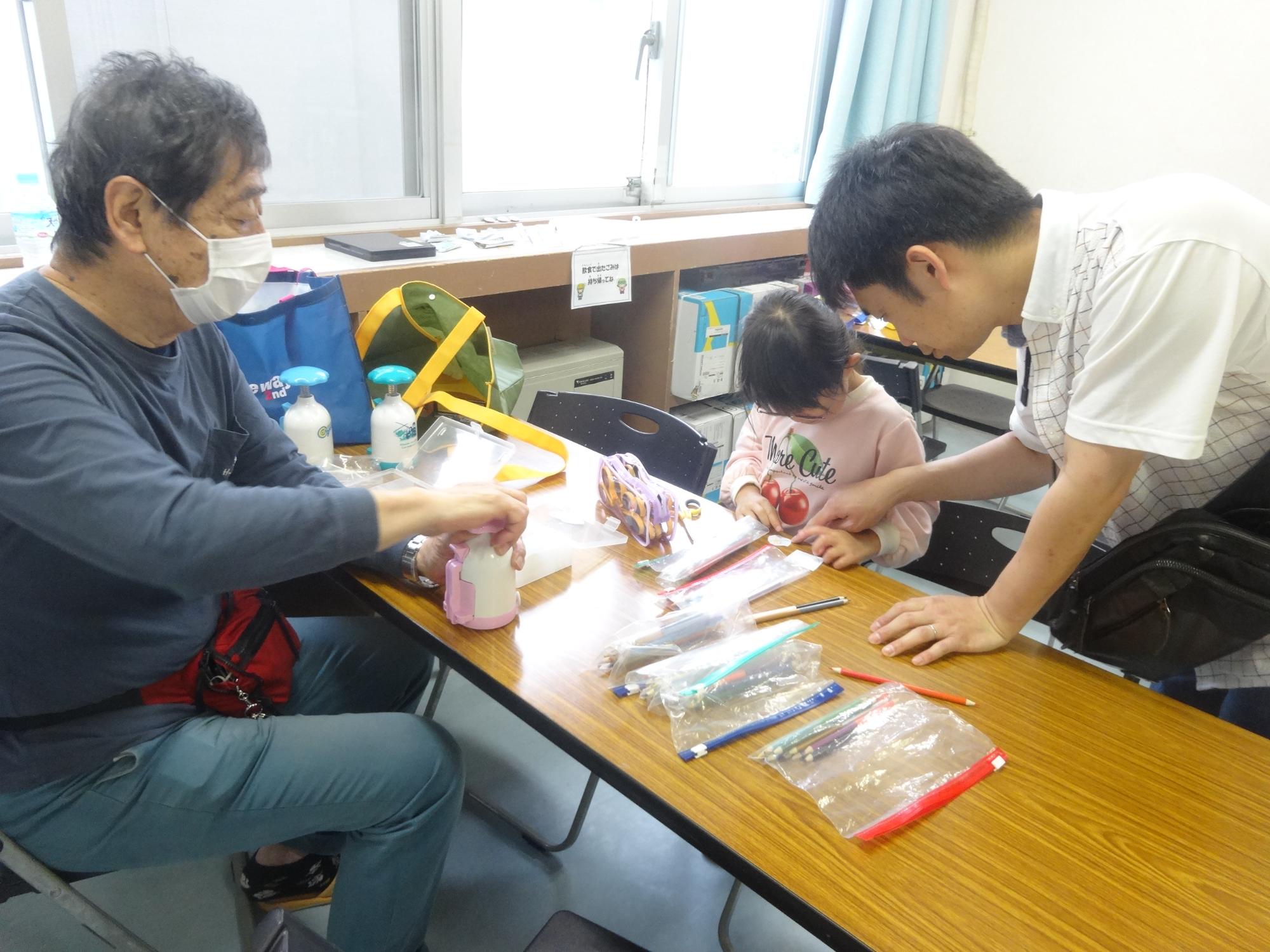 缶バッジの大きさに合わせてイラストをカットする幼児とお父さん