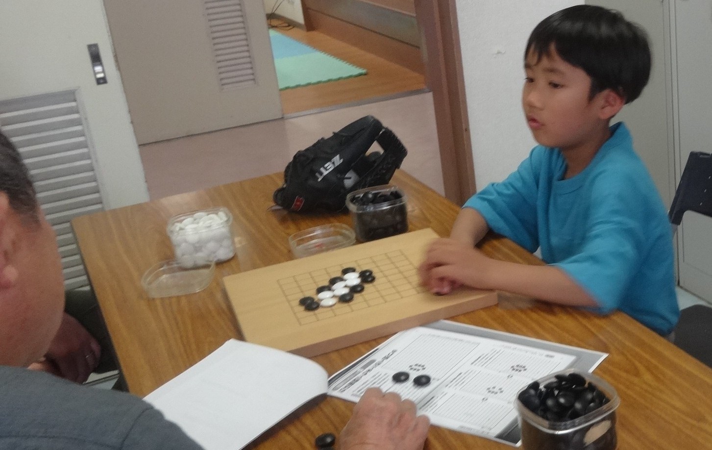 先生と囲碁の対局をしながらルールを学んでいる小学生の写真
