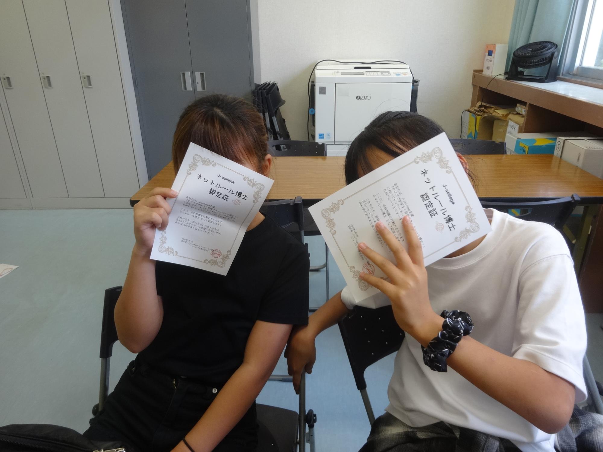 ネットルール博士認定証で顔を隠す二人の小学生の写真
