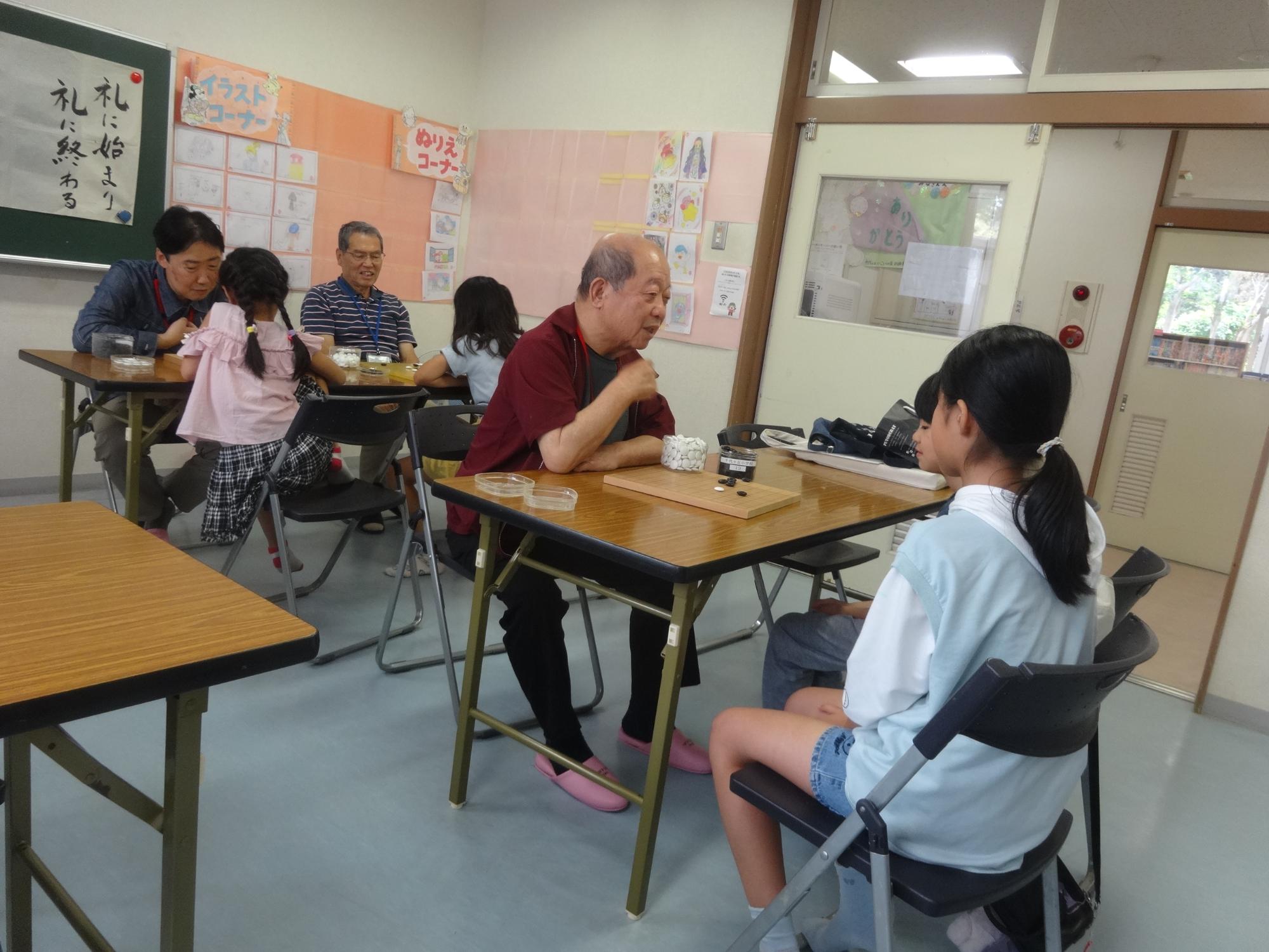 先生と囲碁の対局をしながらルールを学んでいる小学生の写真