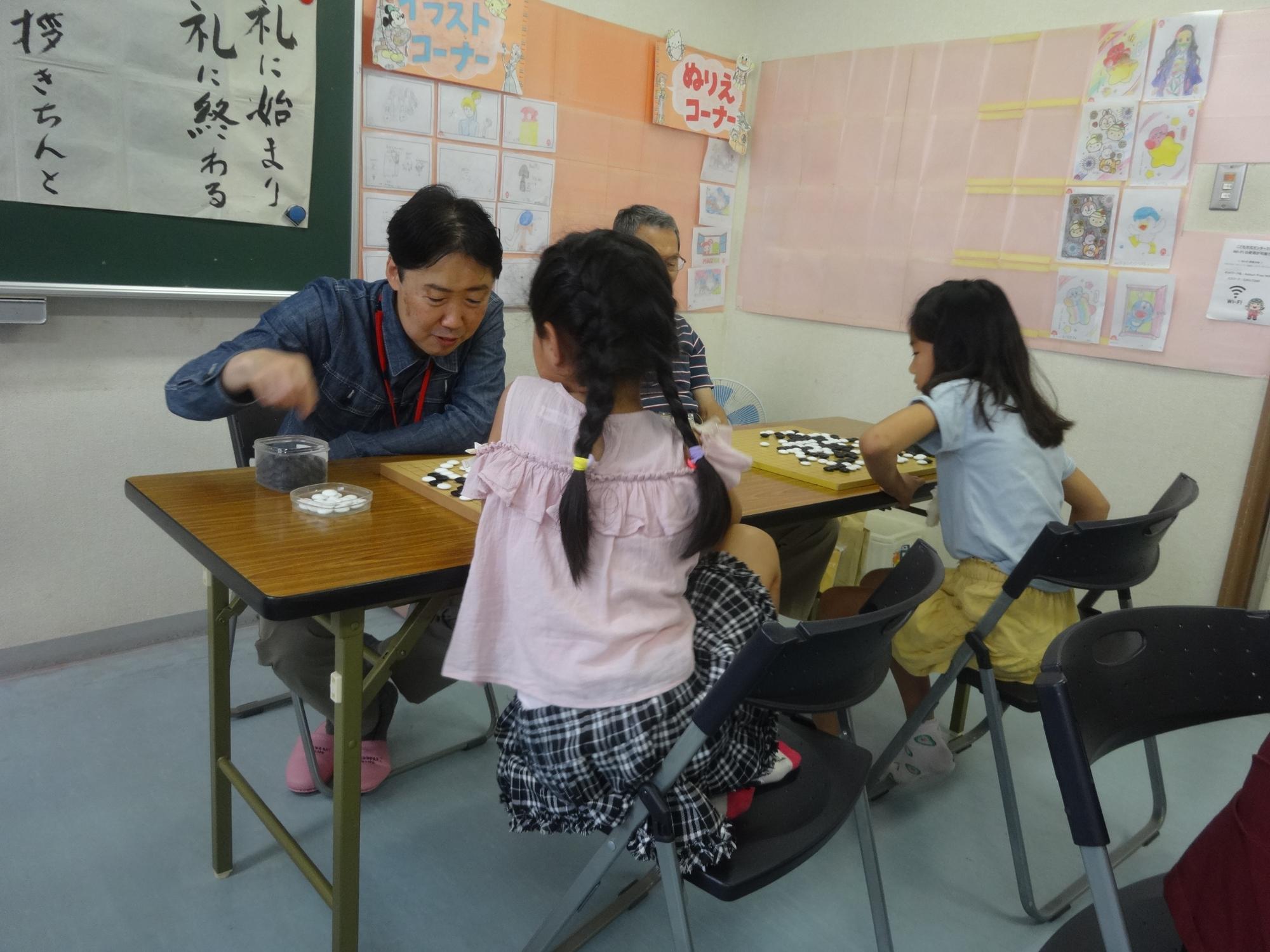 先生と対局し、次の手を考えている小学生の写真