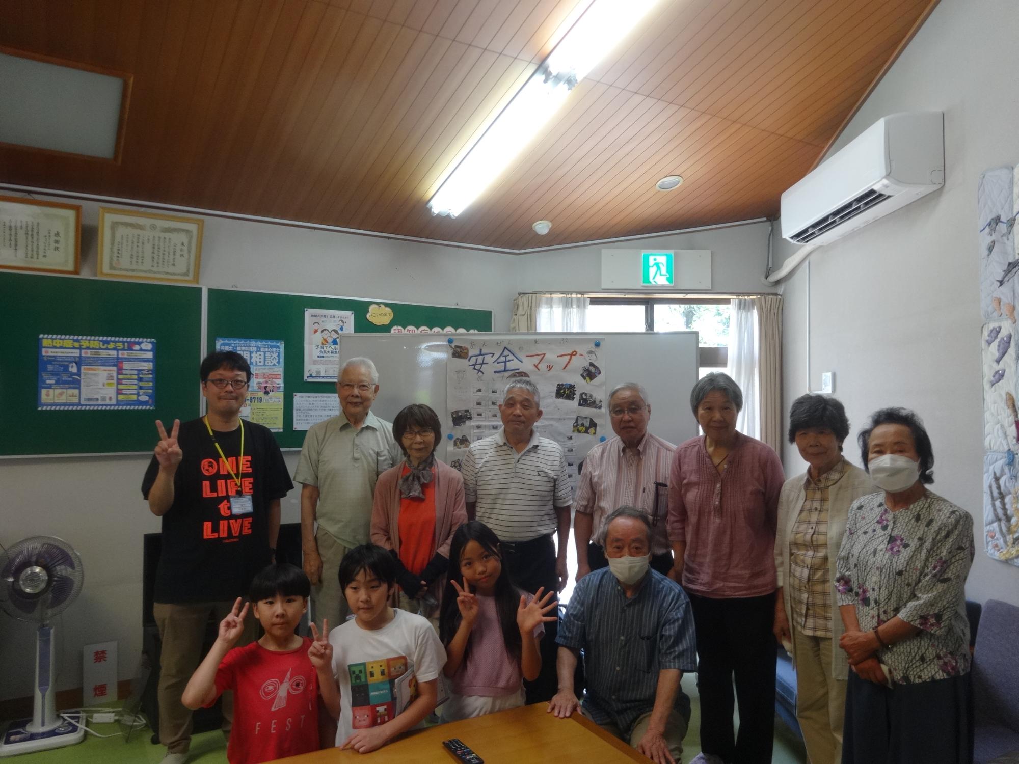 老人いこいの家で安全マップの説明をした小学生三人と、発表を聞いてくださった来館者のみなさんとの集合写真