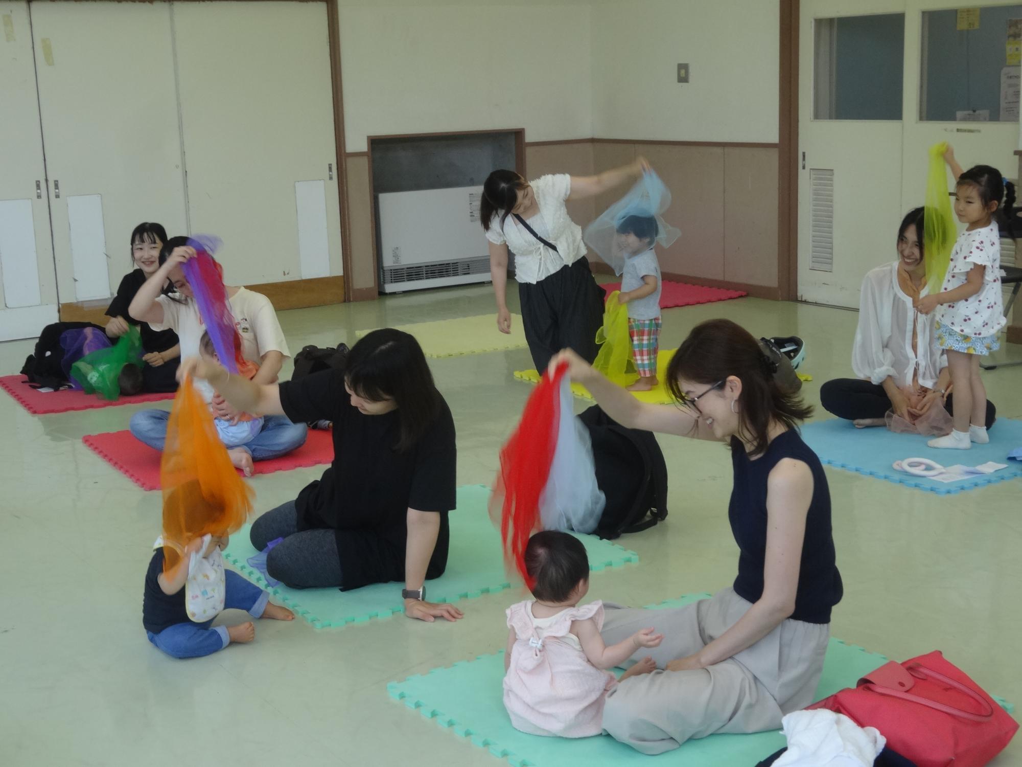 音に合わせて布で遊ぶ赤ちゃんとお母さんの写真