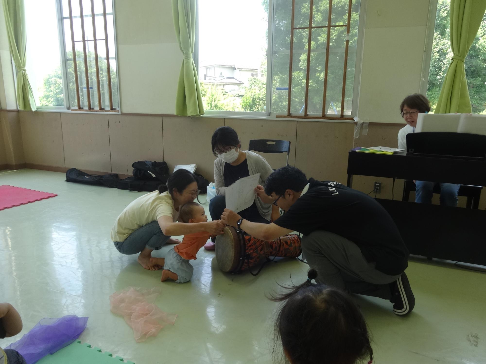 大きな太鼓に手を伸ばす赤ちゃんの写真
