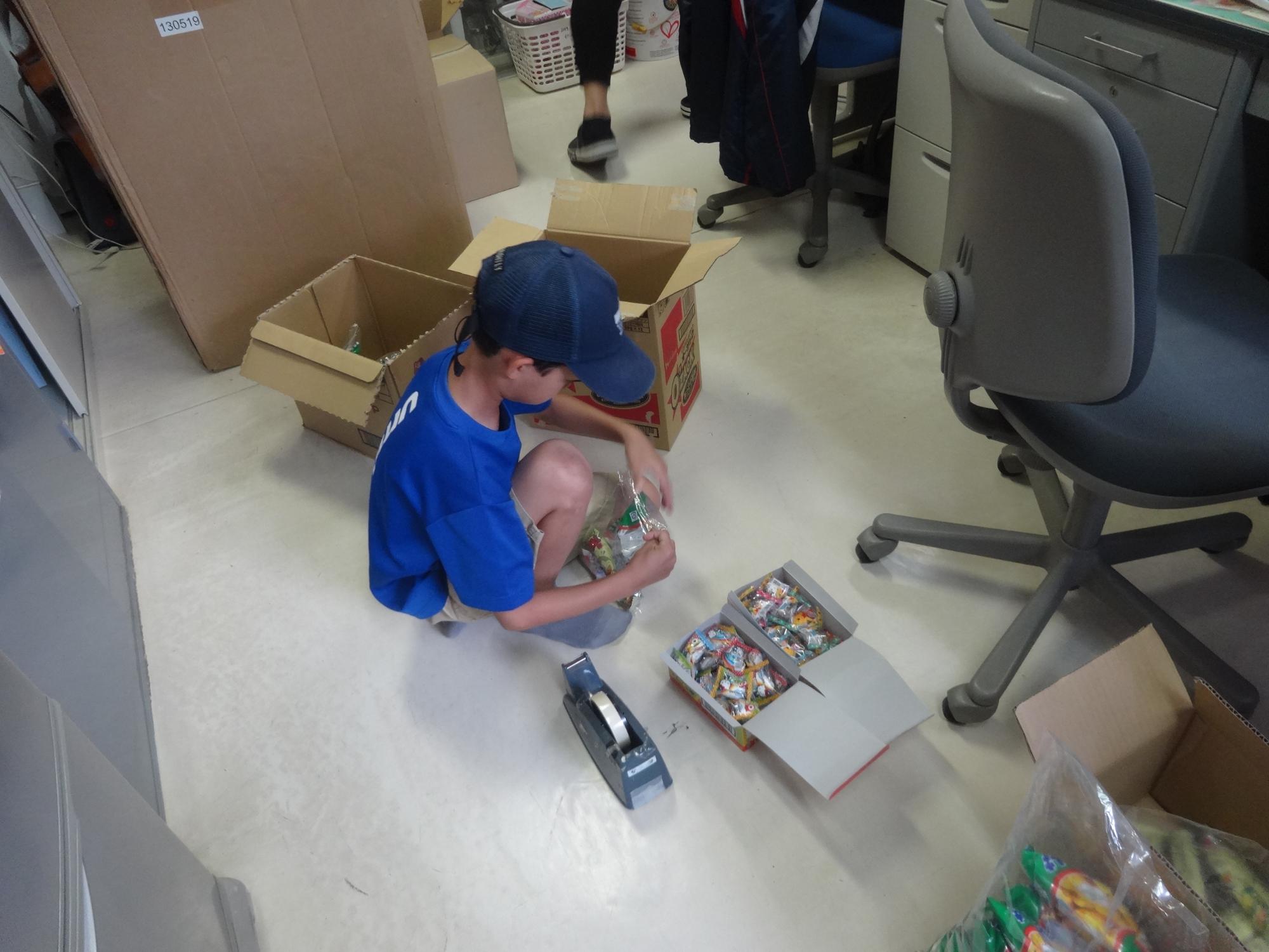 ワンダーハッピーシネマで配るお菓子を袋に詰める作業をする小学生