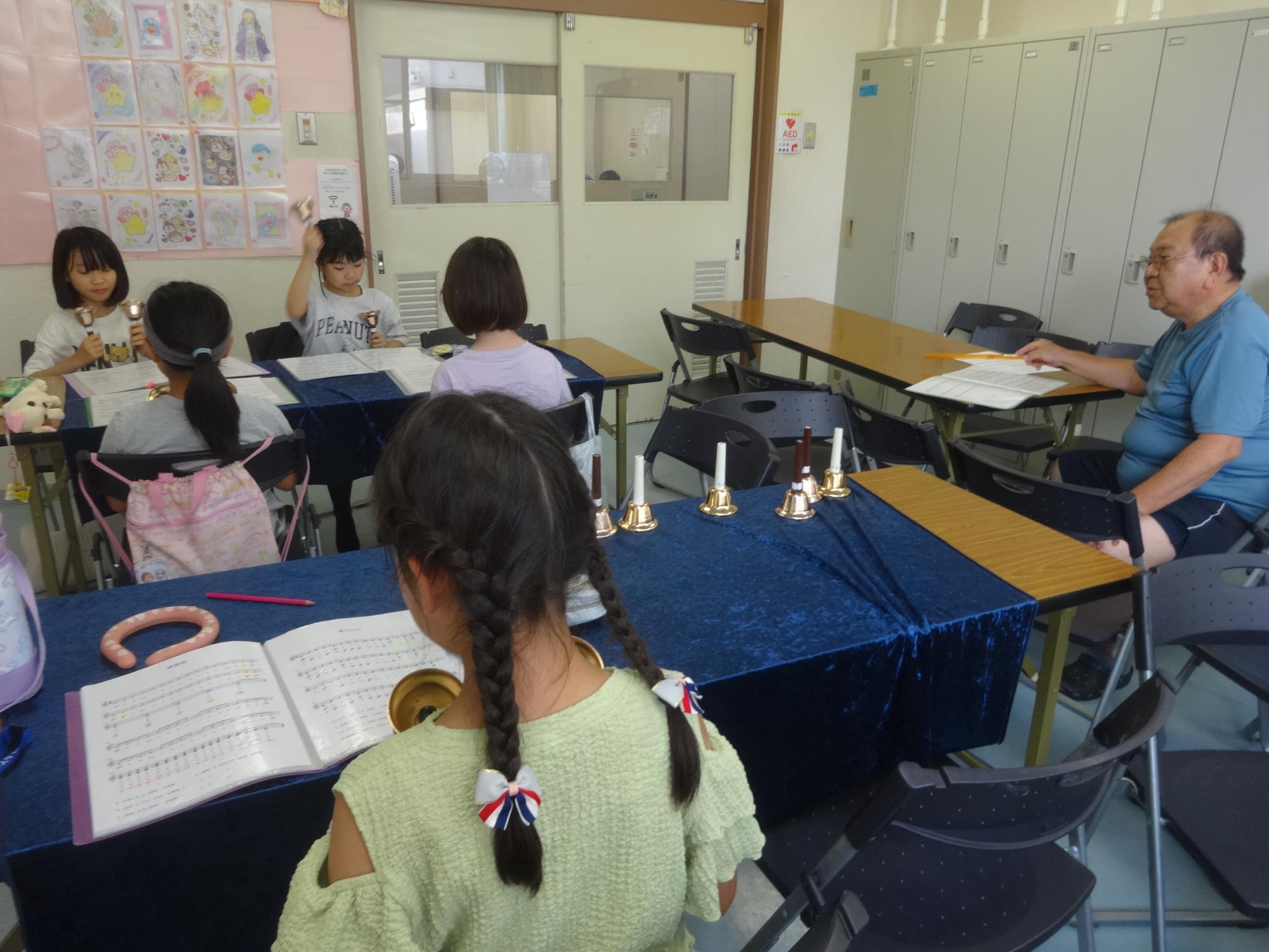 ハンドベルの先生と練習をする小学生たち