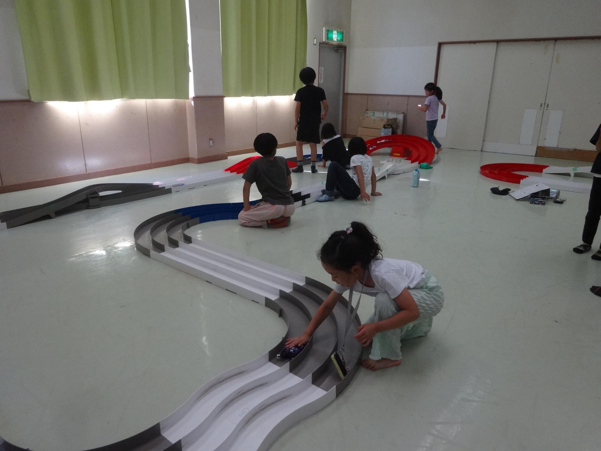 ミニ四駆をコースで走らせる子どもたち