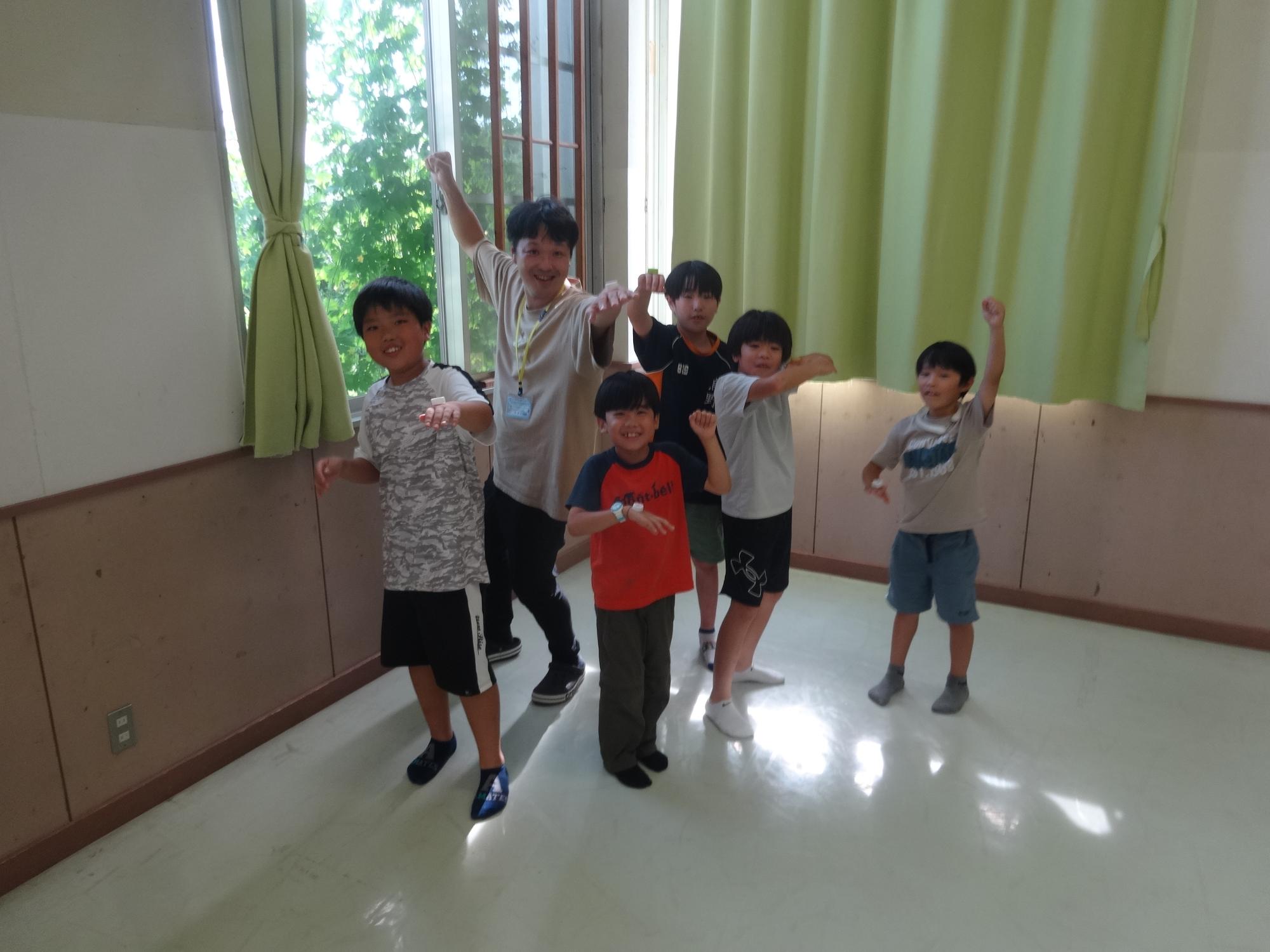 手の甲にペットボトルキャップを乗せてポーズをとる男子6人