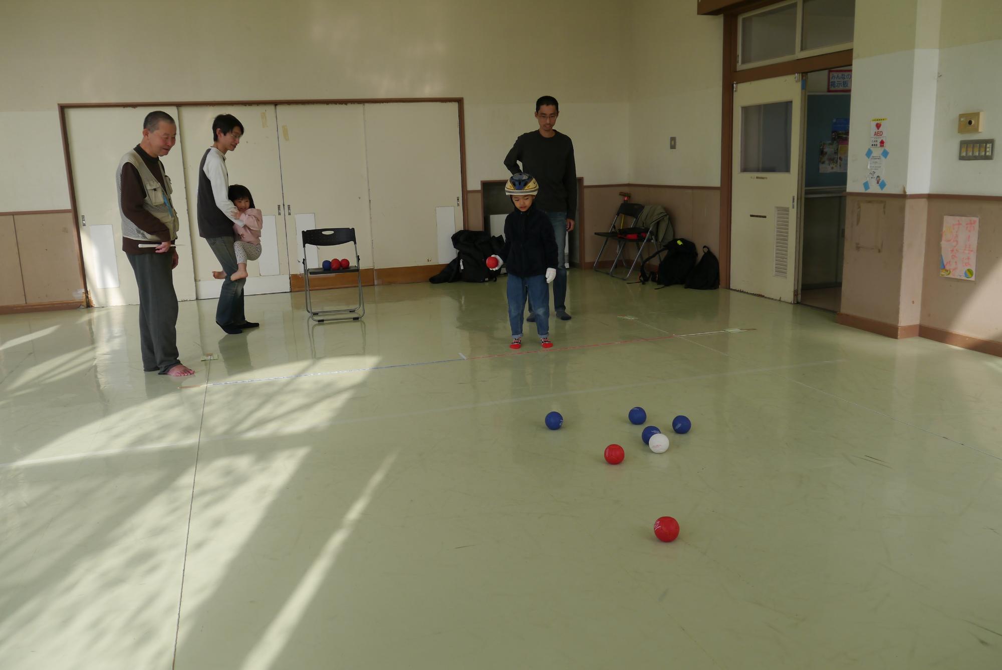 ボールを投げる幼児と見守る保護者