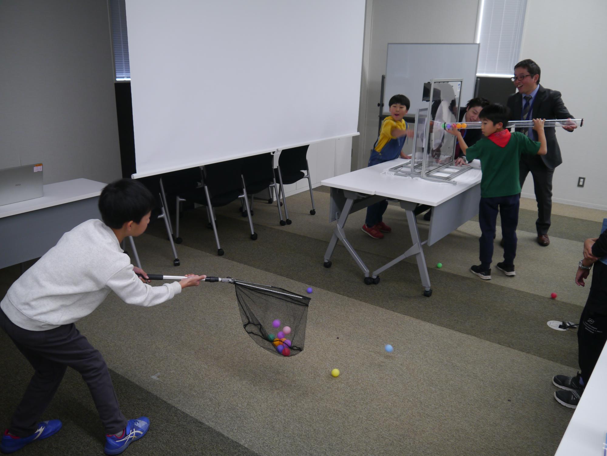 ピンポン玉を飛ばす実験に参加する3人の小学生の写真