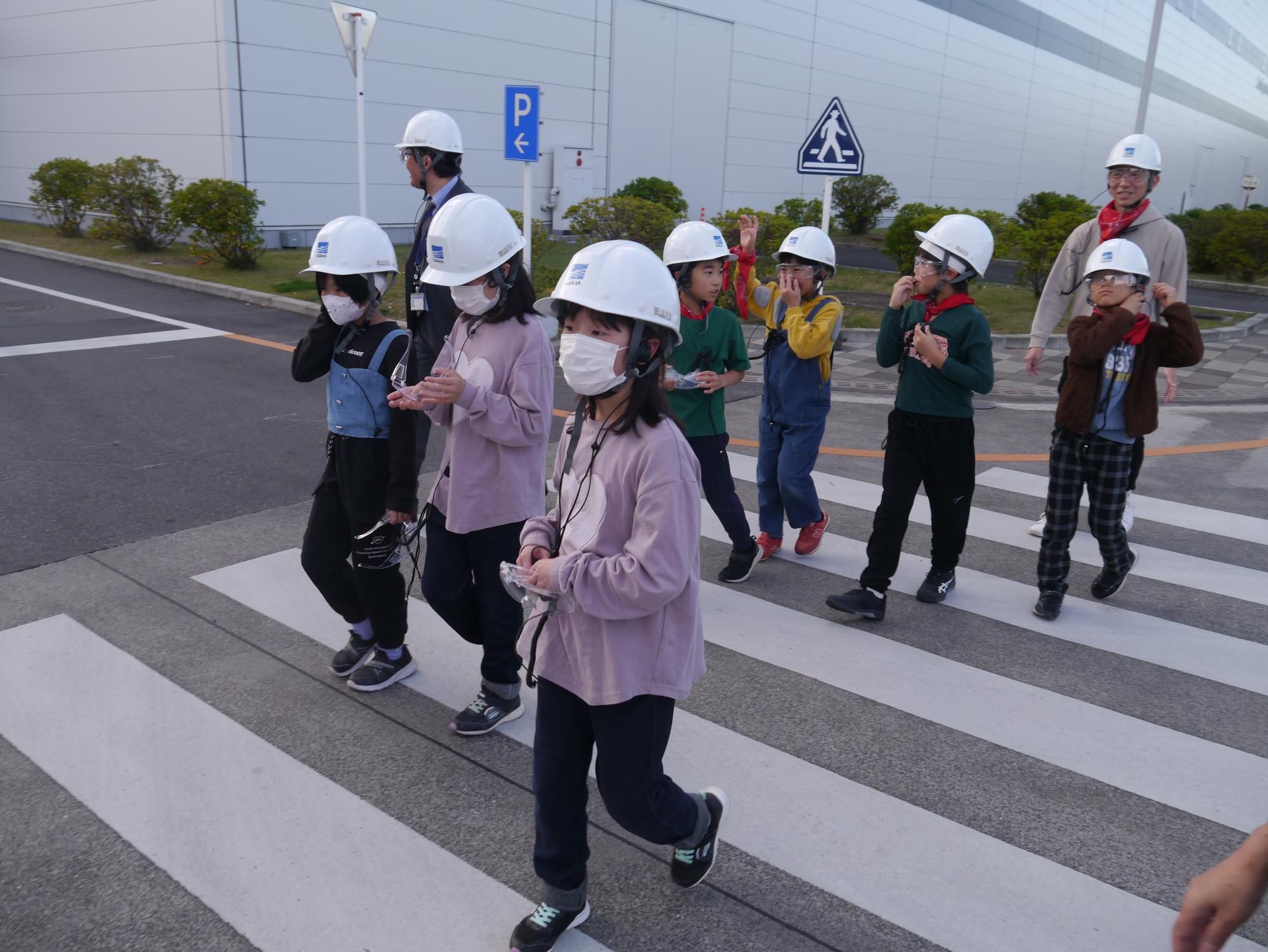 工場内の見学のために、ヘルメットとゴーグルを装着した小学生の写真