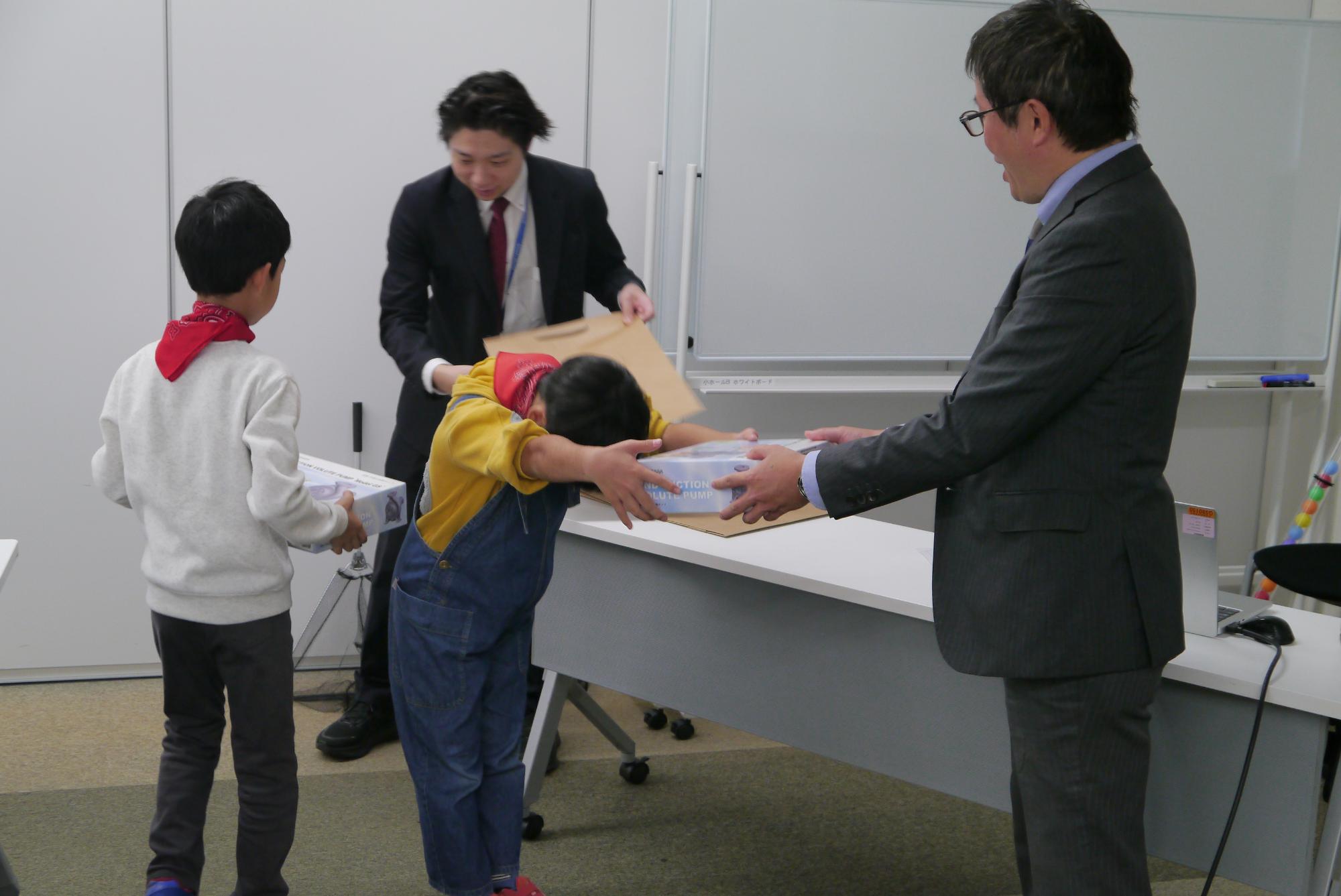 抽選でプレゼントをもらった3人の小学生の写真