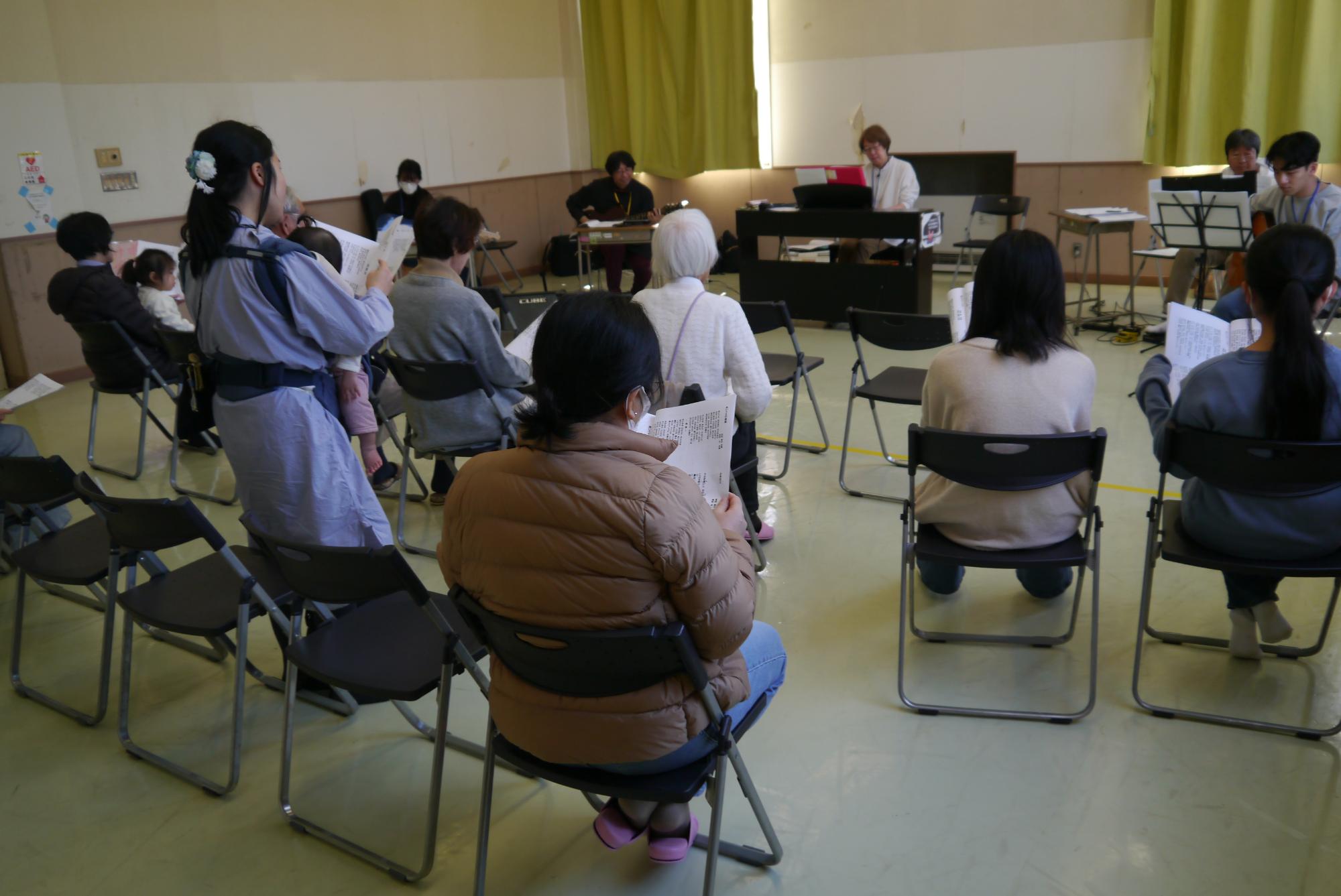 ギター4人とピアノの伴奏で参加者全員で歌を歌う写真