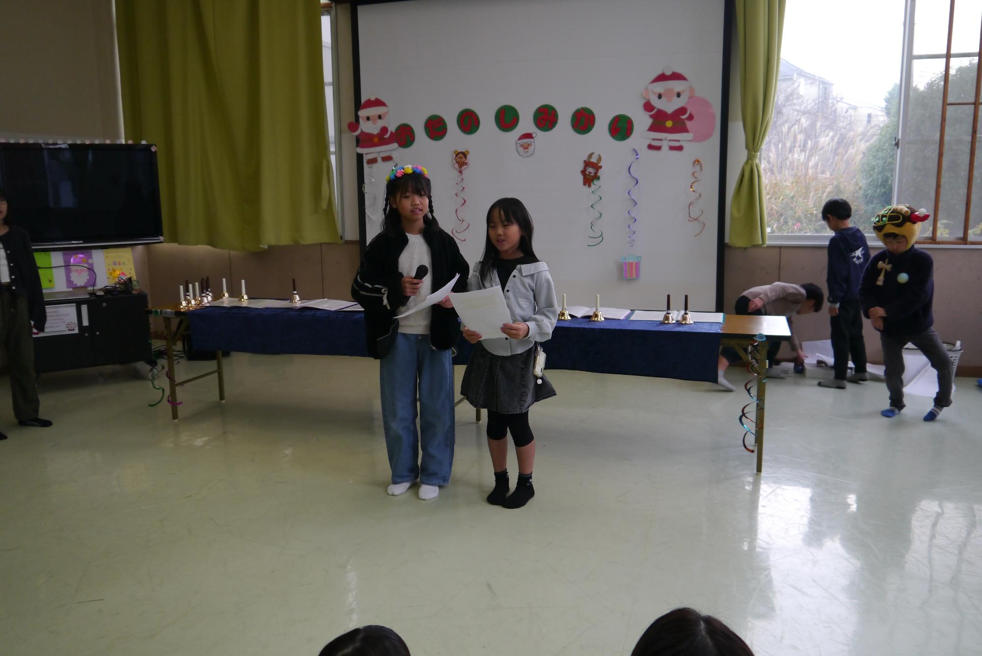 おたのしみ会の司会者の小学生が挨拶を行っている。