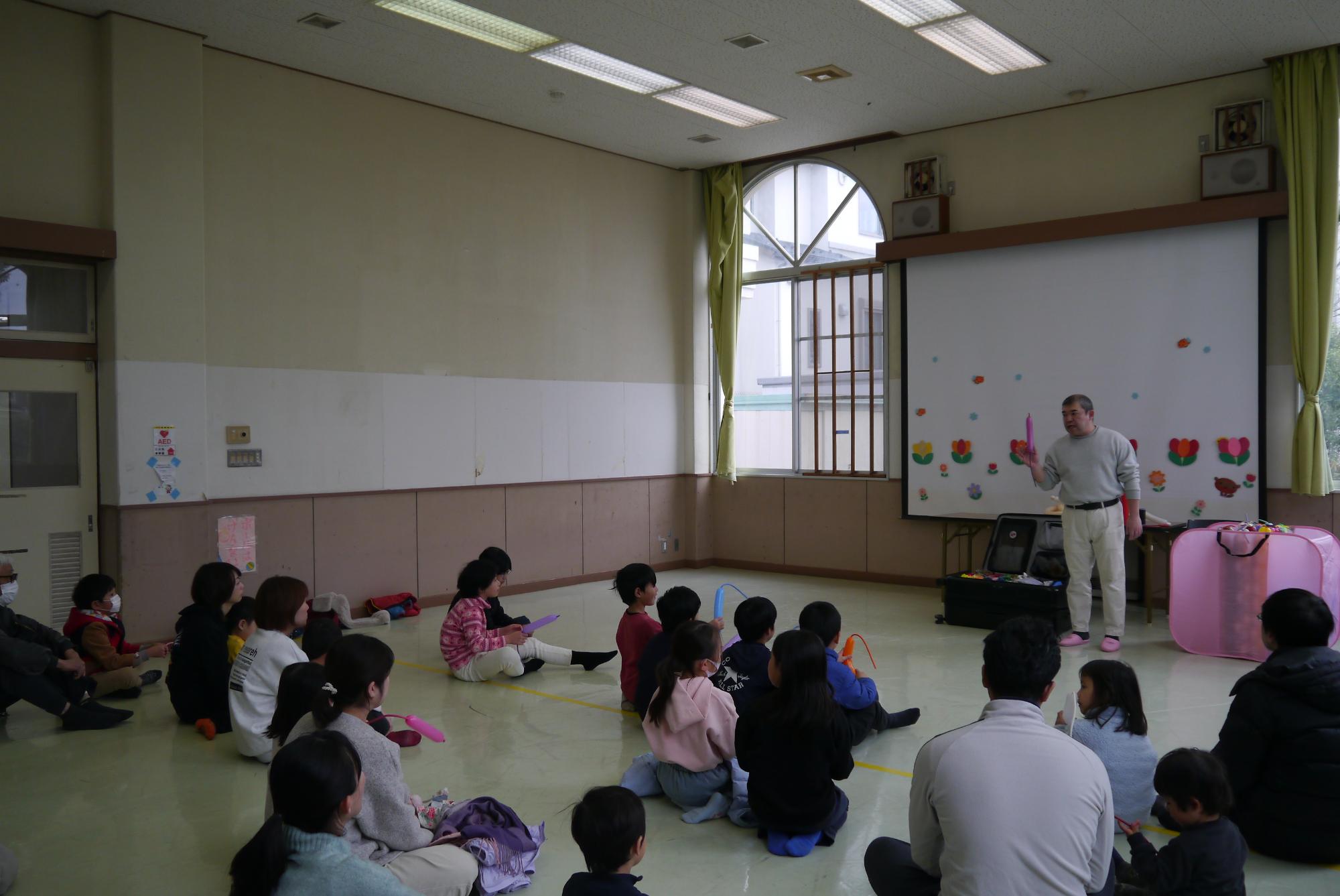 ジャンピングねずみの作り方を解説する講師と話を聞く子どもたち