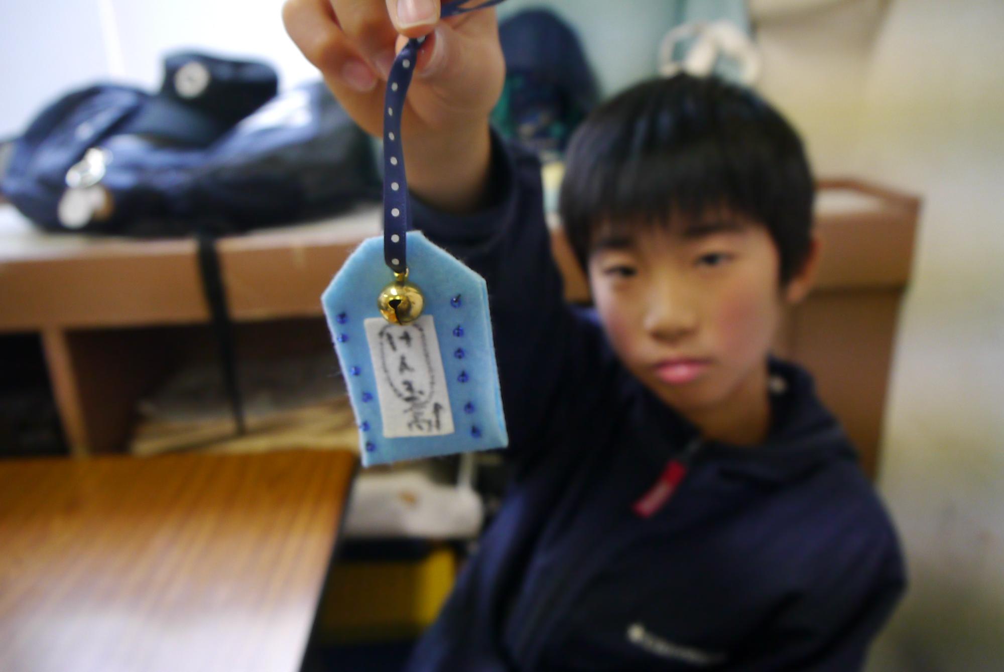 完成したお守りを掲げる小学生の写真