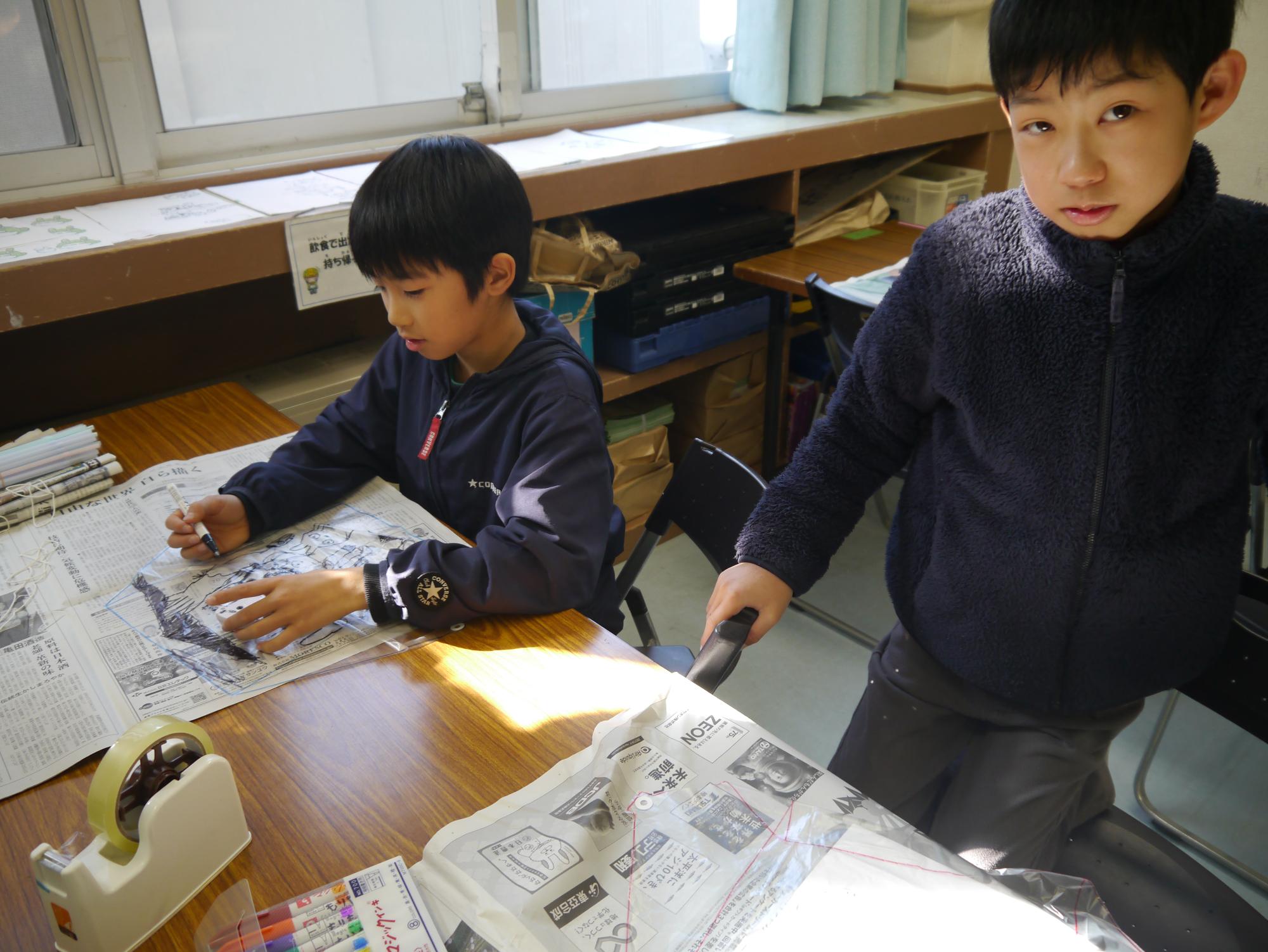 凧に絵を描いている小学生の写真