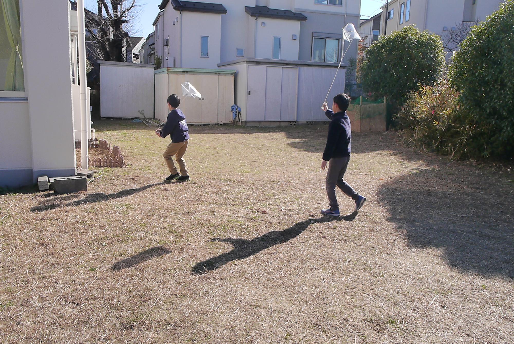 自分で作った凧を公園であげている小学生の写真