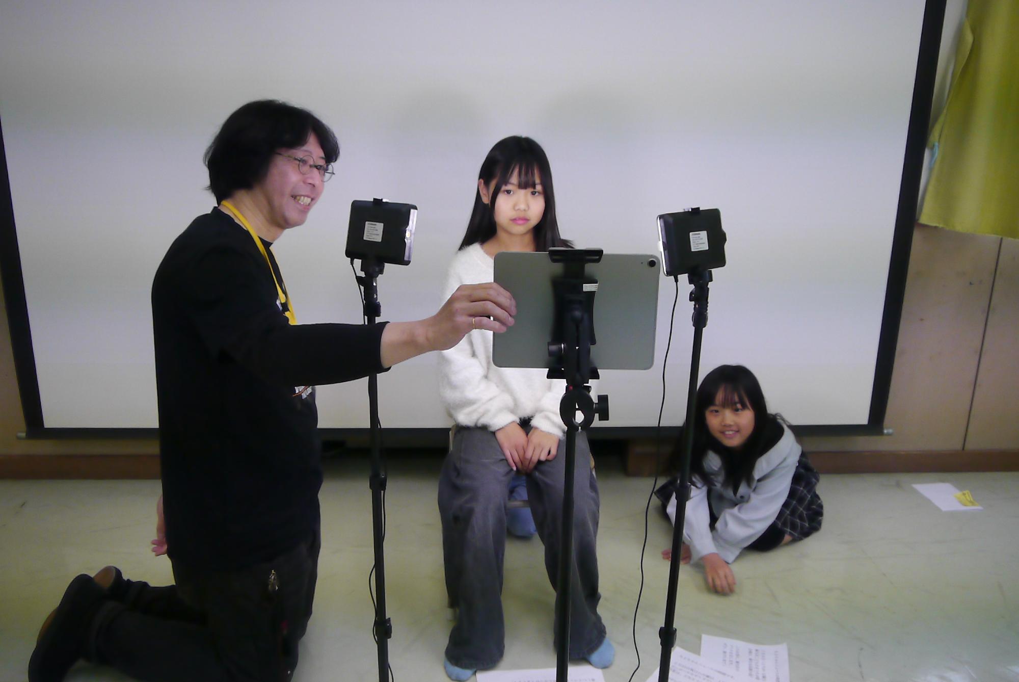 画面の確認をするスタッフと子どもたちの写真