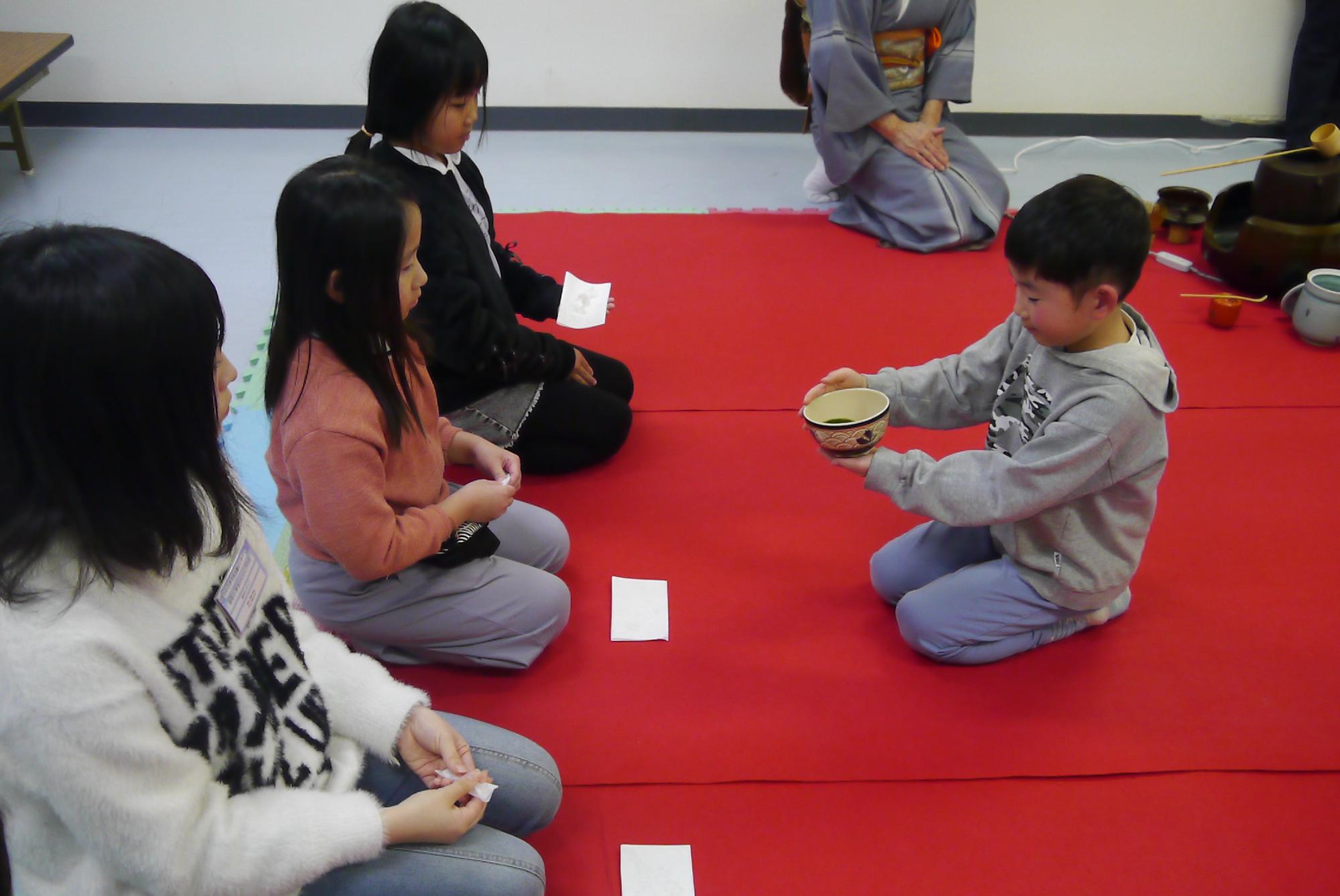 立てたお茶を相手に振舞う小学生の写真