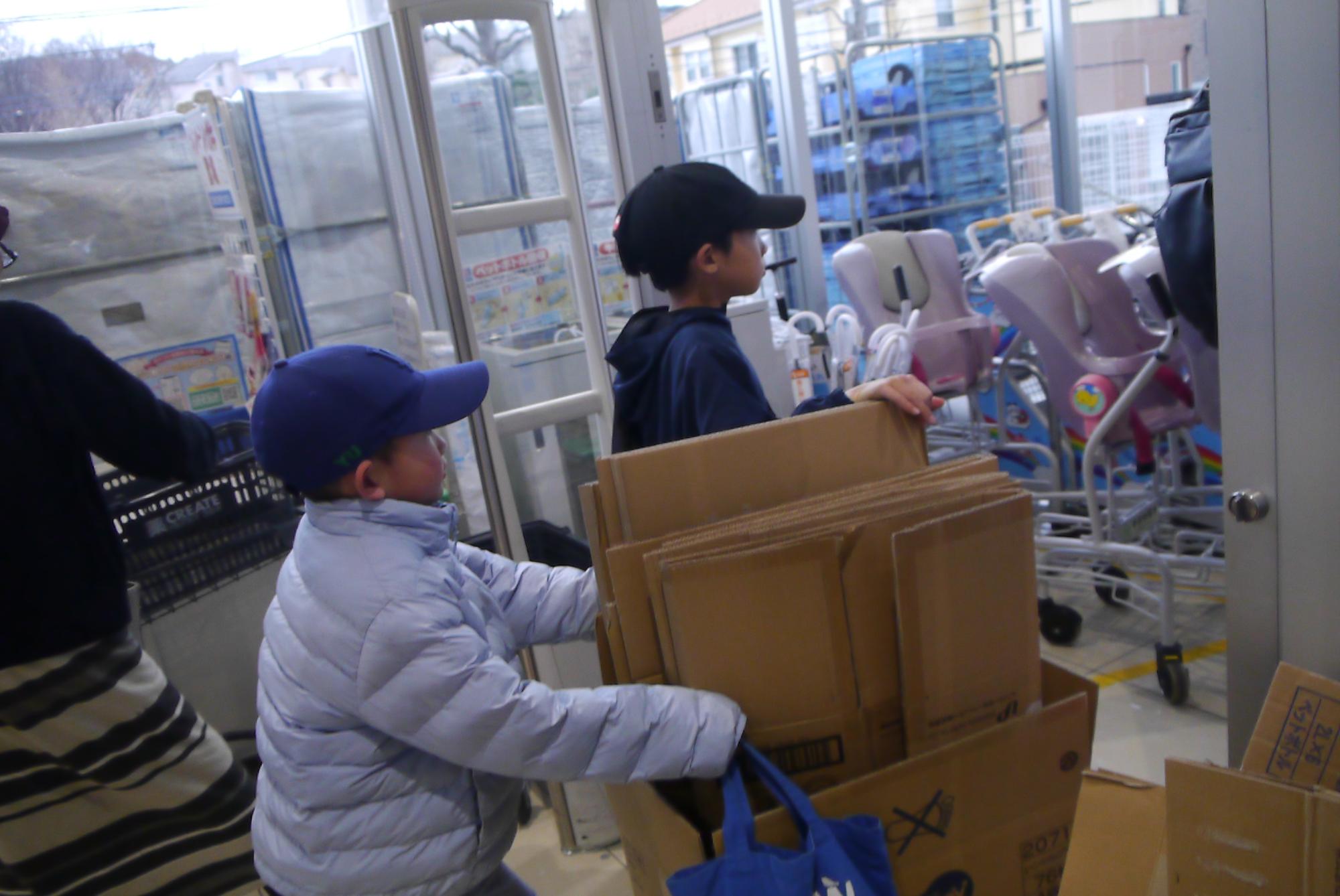 段ボールを集めにドラッグストアに行くふたりの小学生の写真