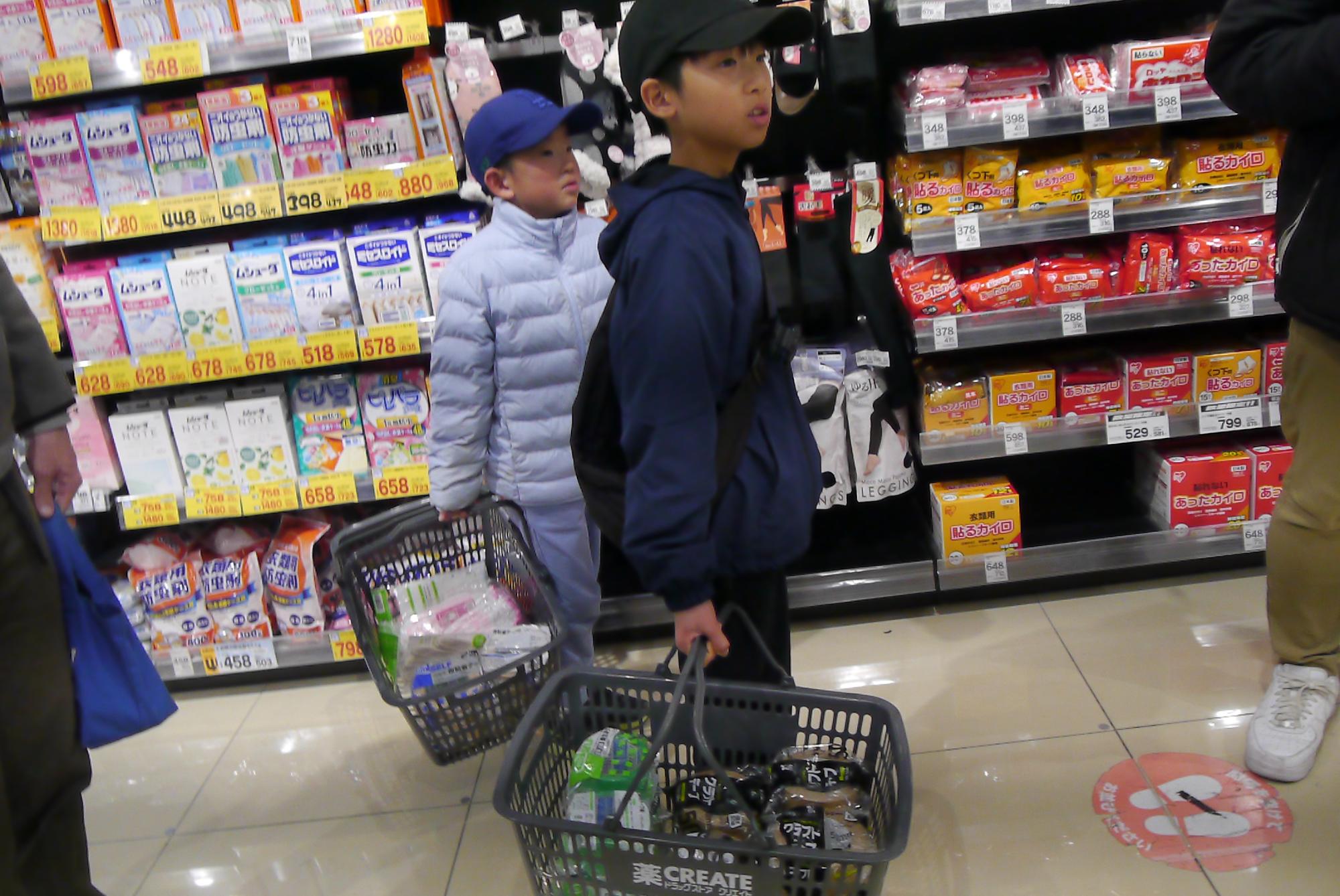 ダンボールハウスの材料を買い物する小学生の写真