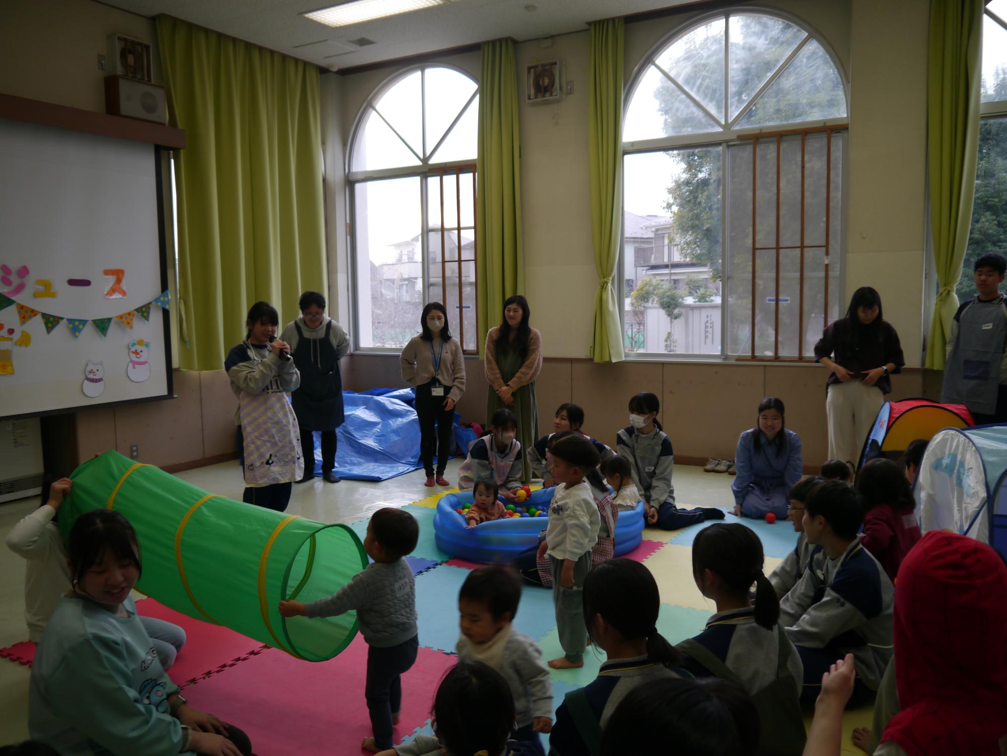 中学生と乳幼児親子が遊んでいる写真