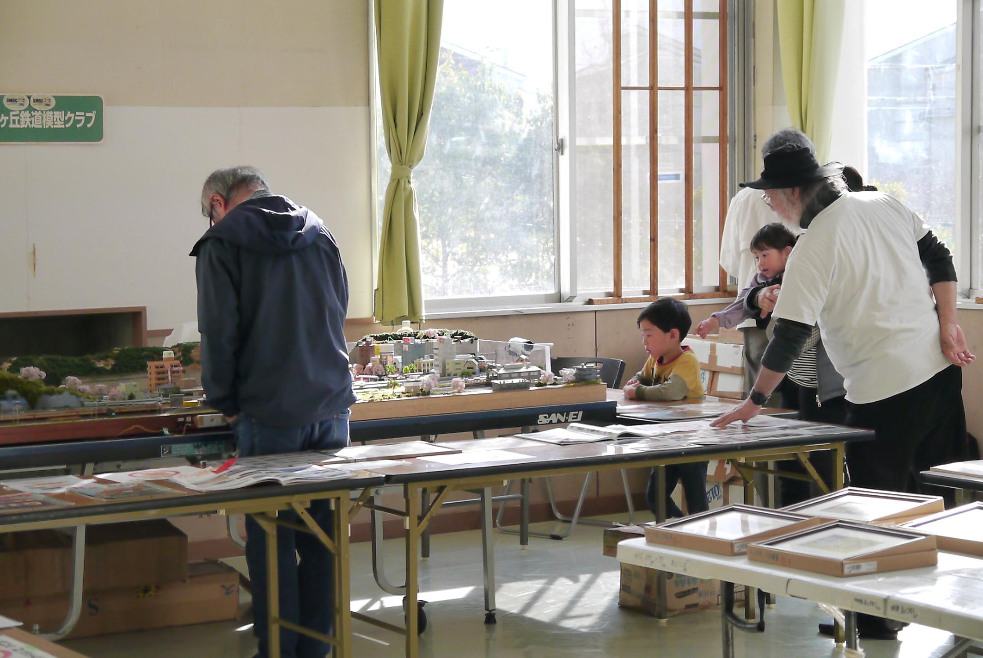 鉄道模型クラブのスタッフから電車の説明を受ける親子