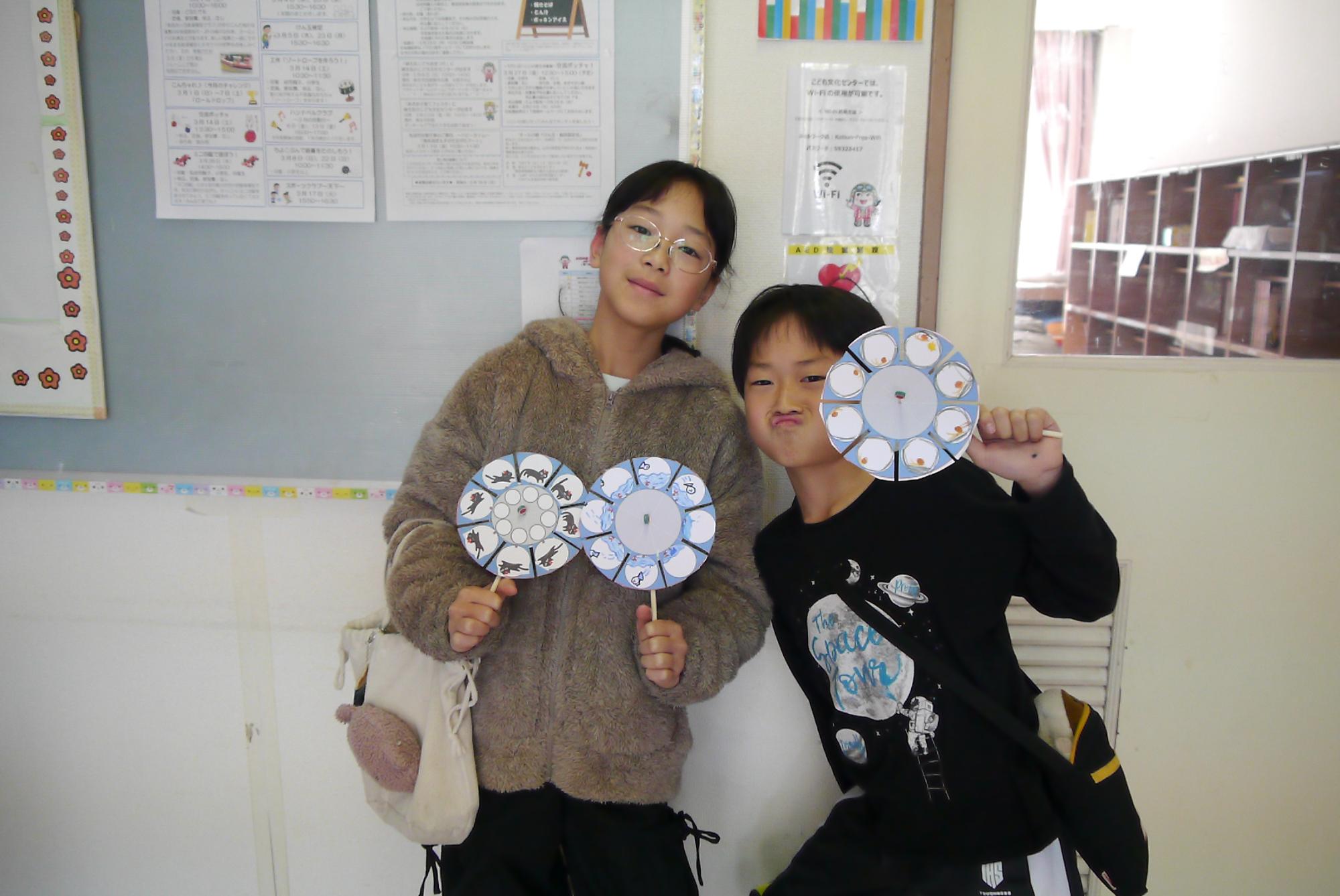 完成したゾートロープと一緒にポーズをとる姉弟