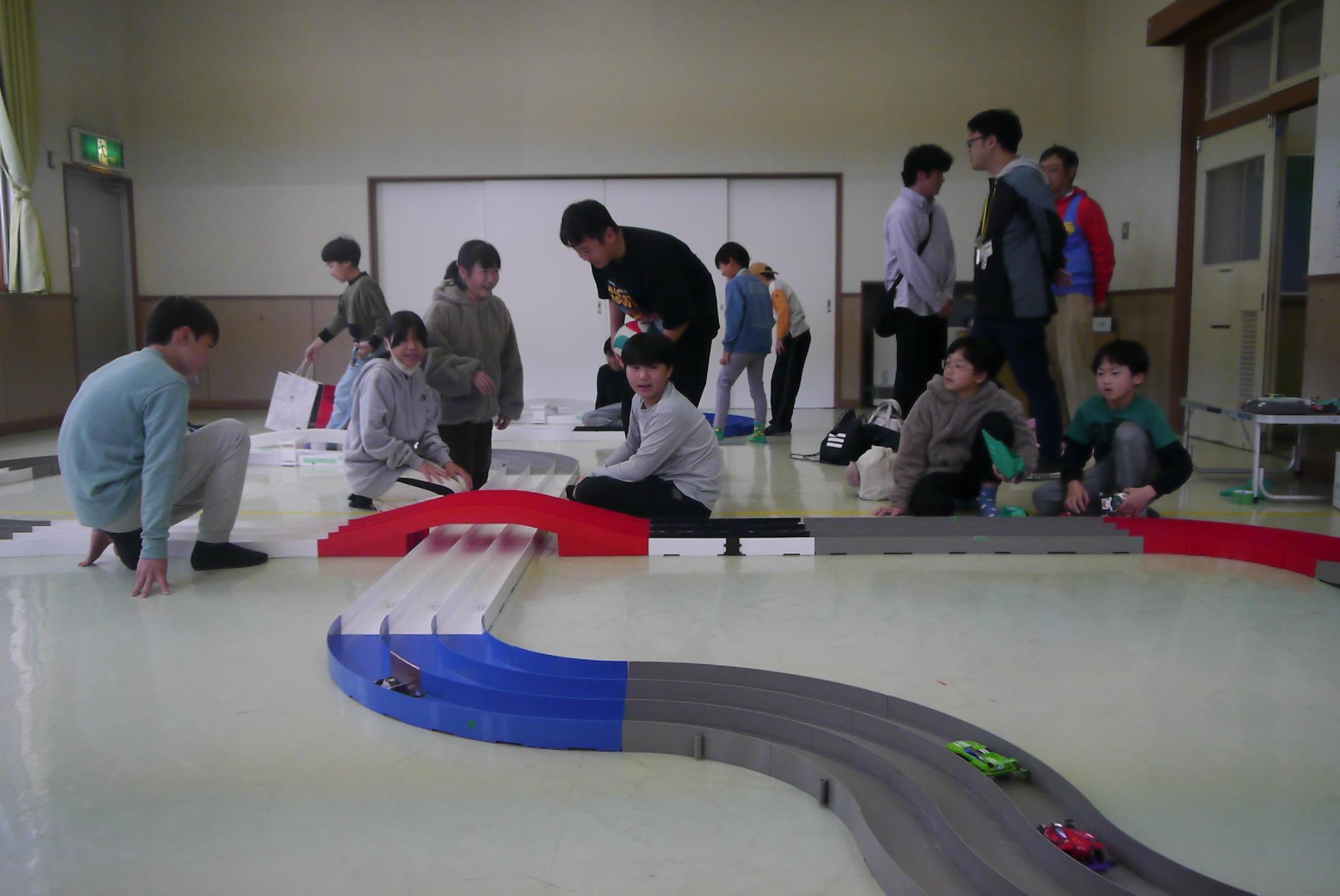 コースを走るミニ四駆の車と子どもたち