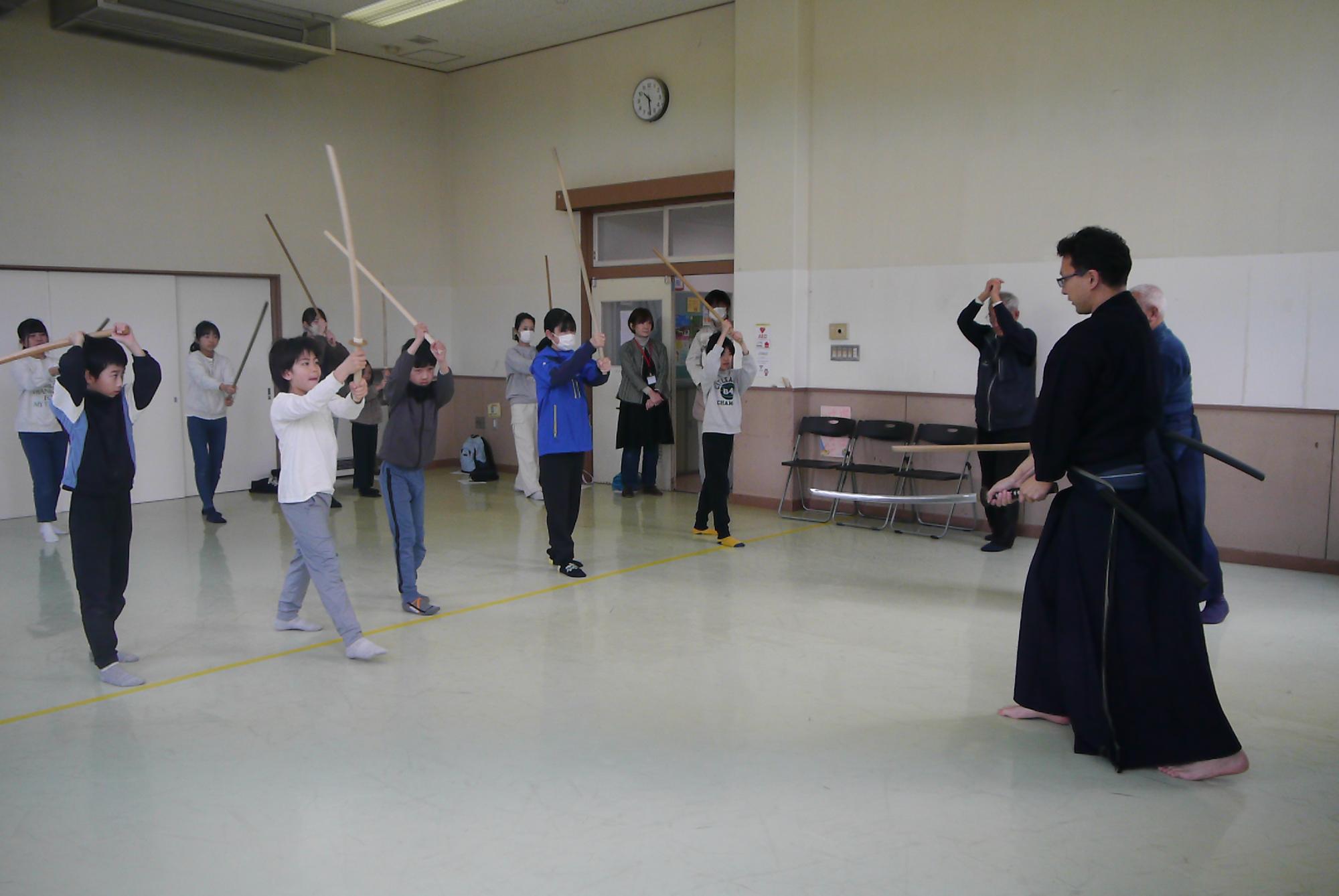 素振りをする先生と子どもたち