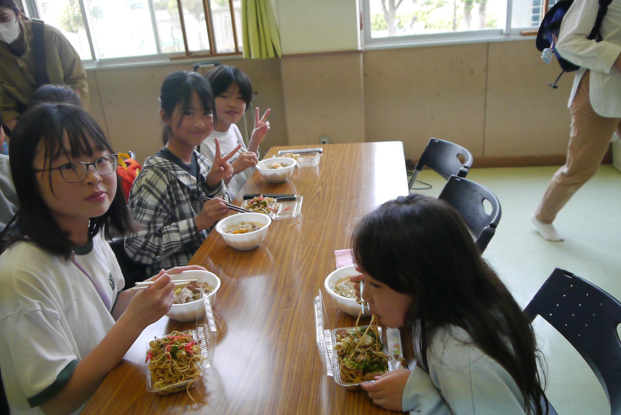 スリーコイン食堂で焼きそばと豚汁を長机で食べる小学生の写真