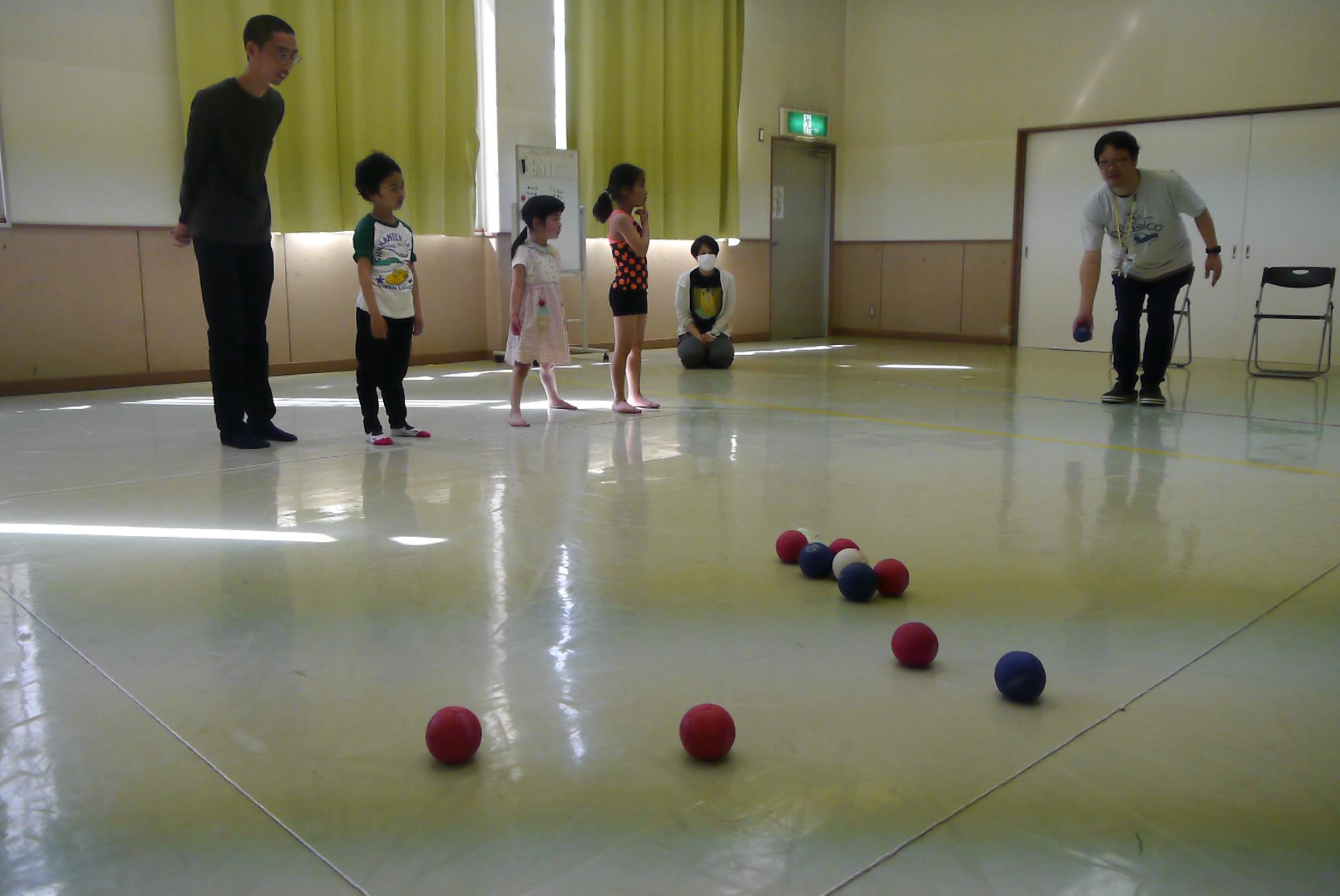 ボールを投げる館長と見守る子どもたち