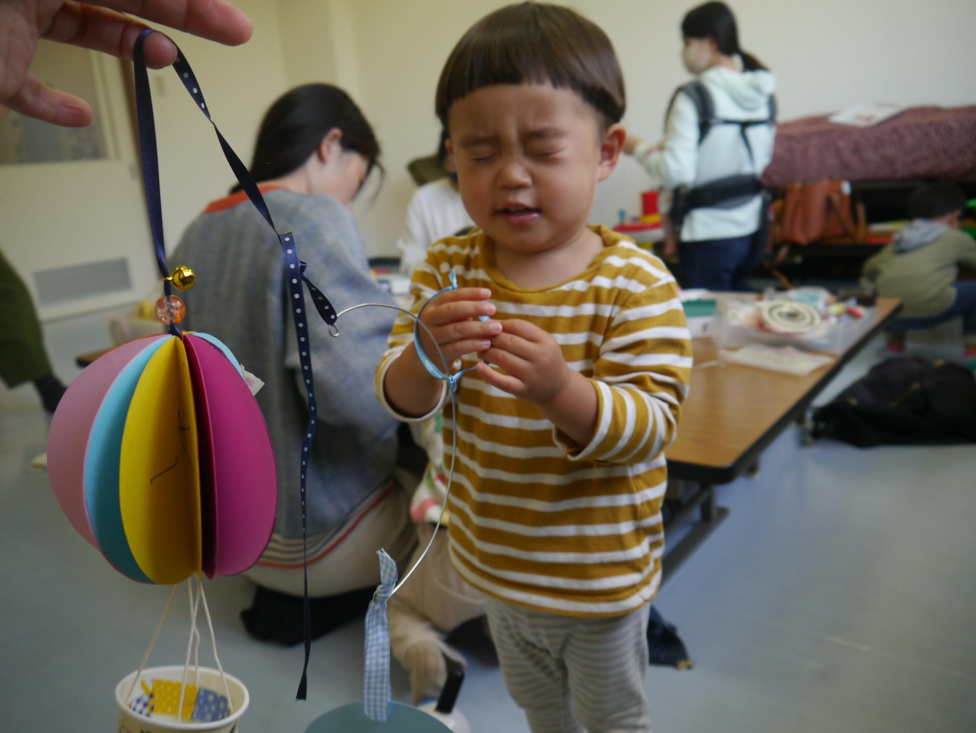 作ったモビールを持っている幼児