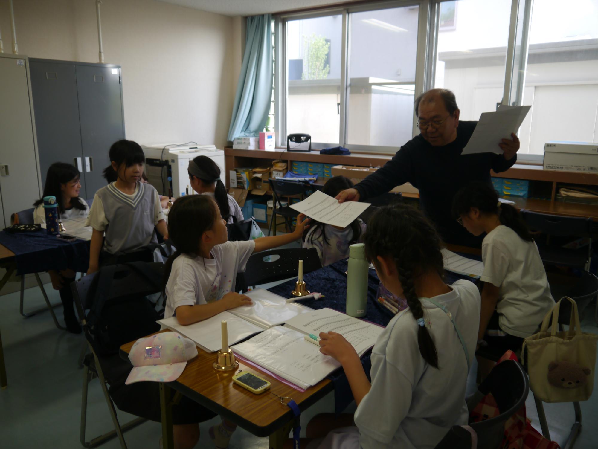先生から楽譜をもらう小学生