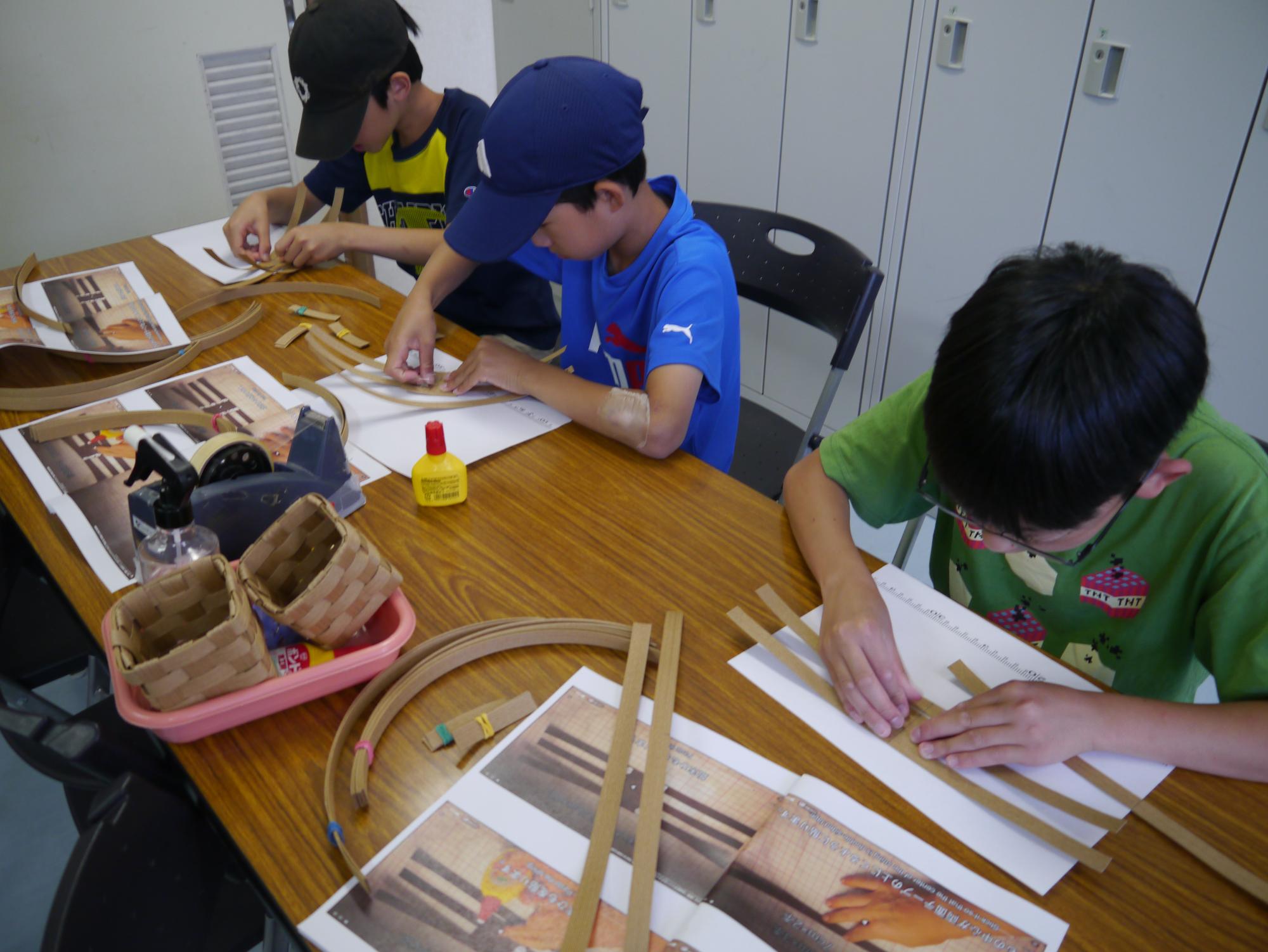 かごを作る小学生男子3人
