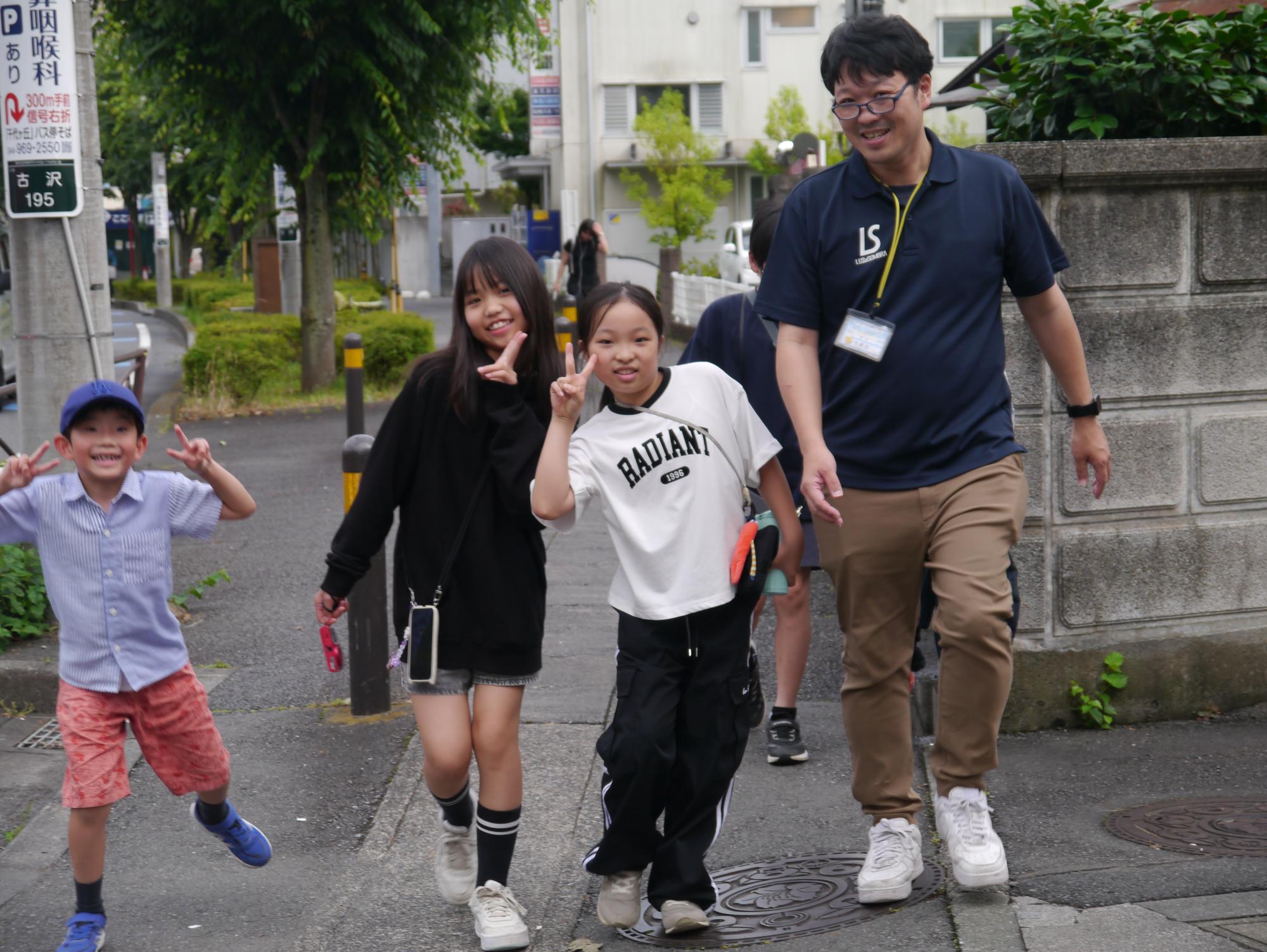 館長と小学生3人が公道を歩きながらピースをしている写真