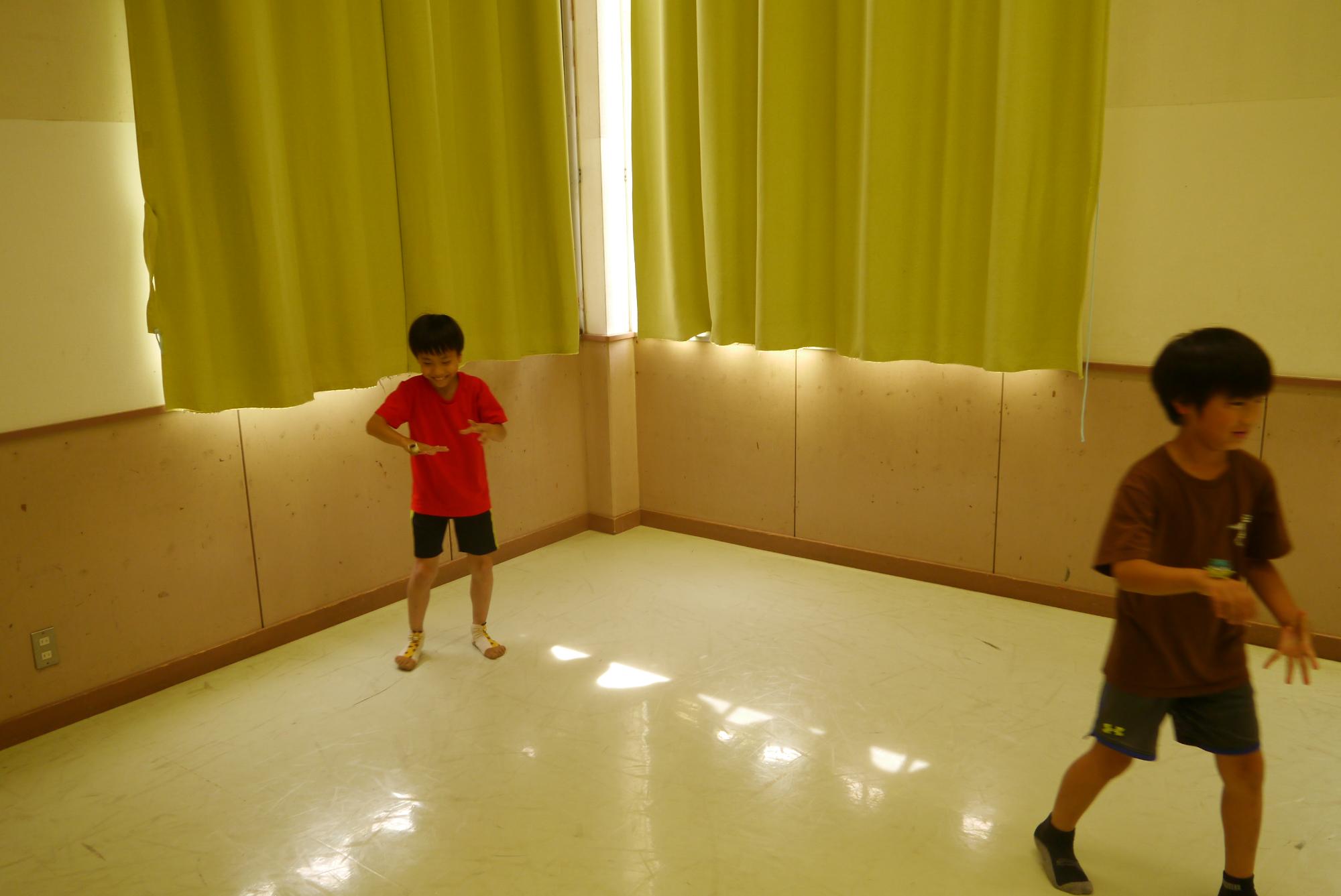 手のこうに小さな人形を乗せ、バランスを考えながら歩き回る小学生の写真