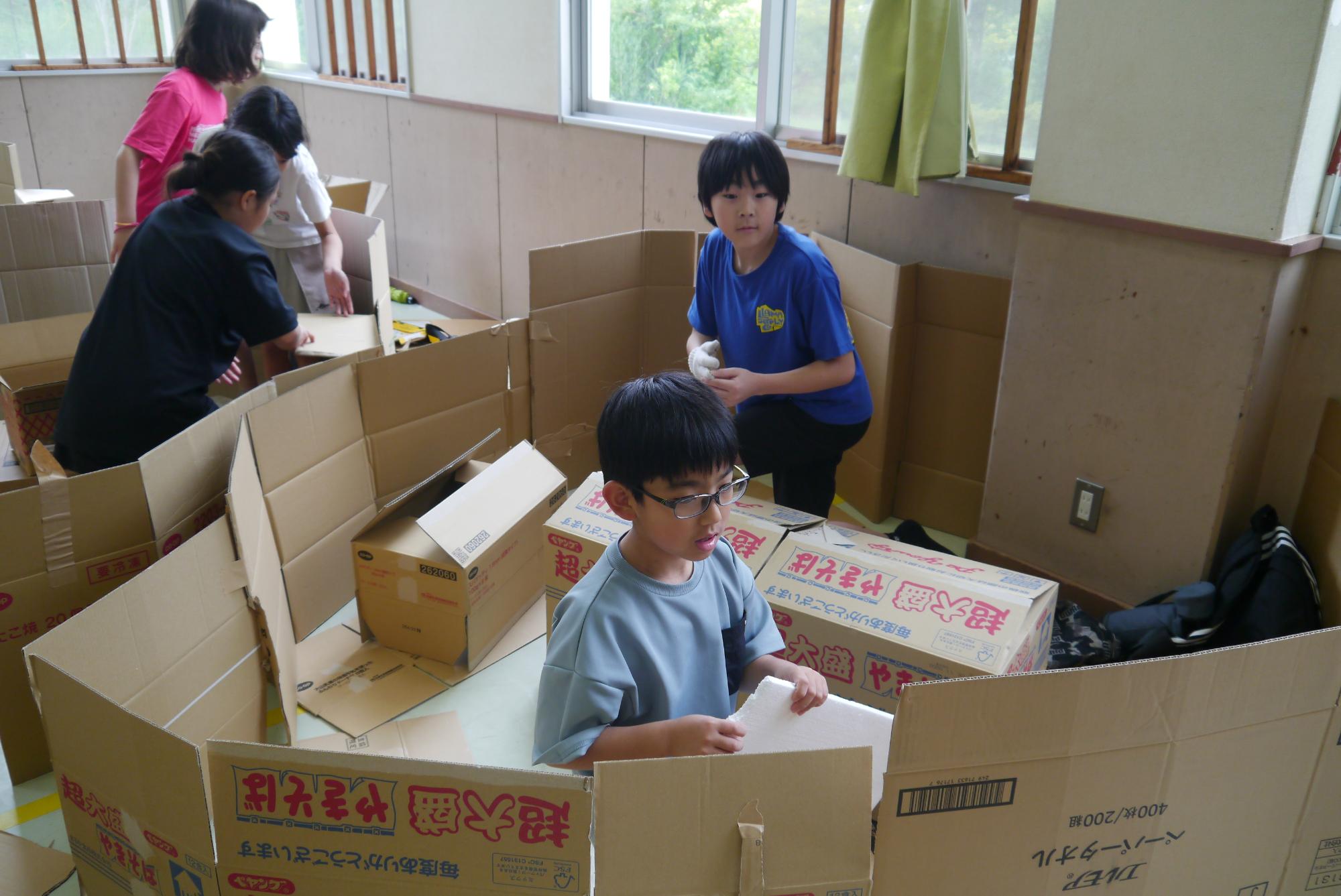 ダンボールを使って家を作る子どもたち