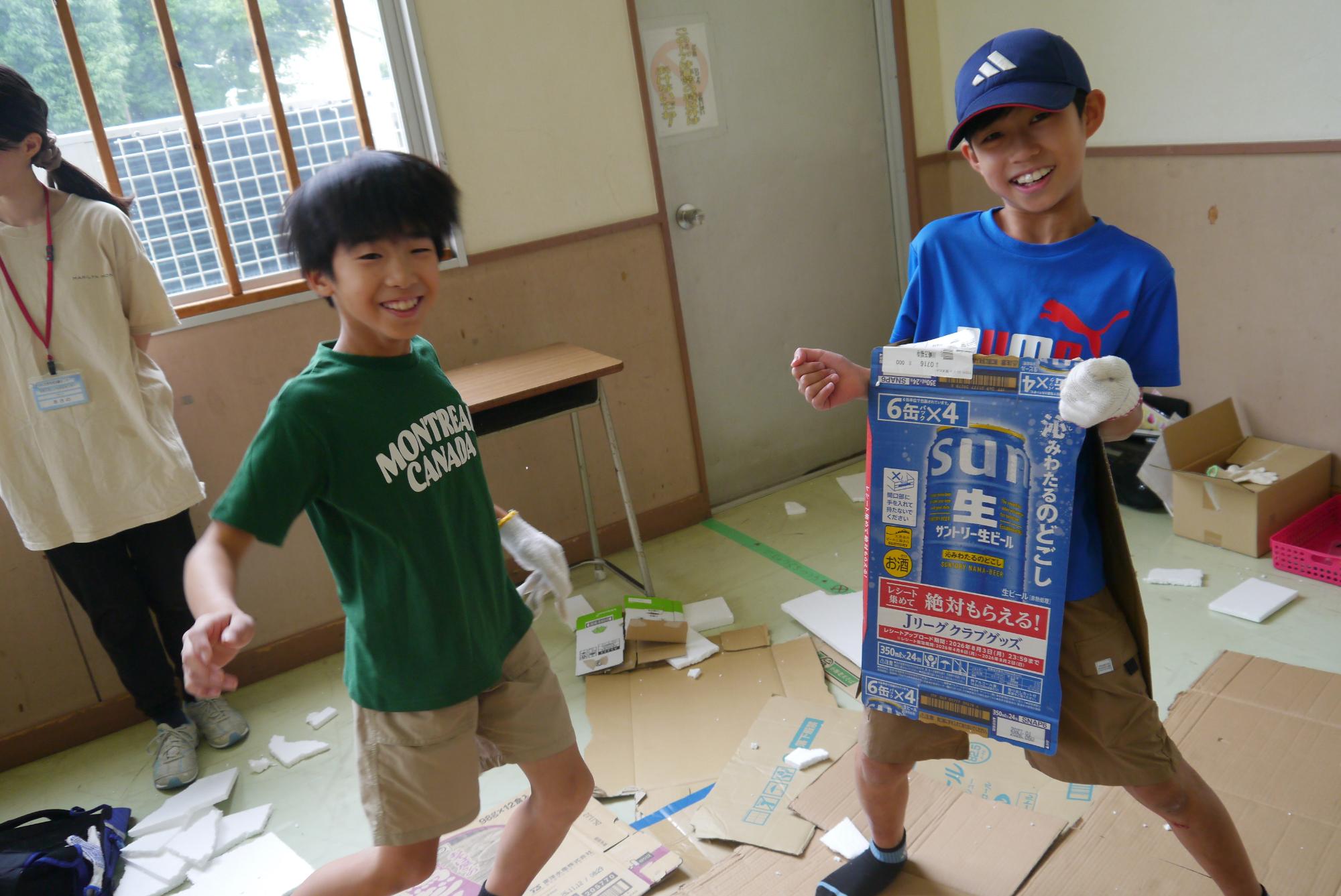 ダンボールを持ってポーズをとる小学生男子二人