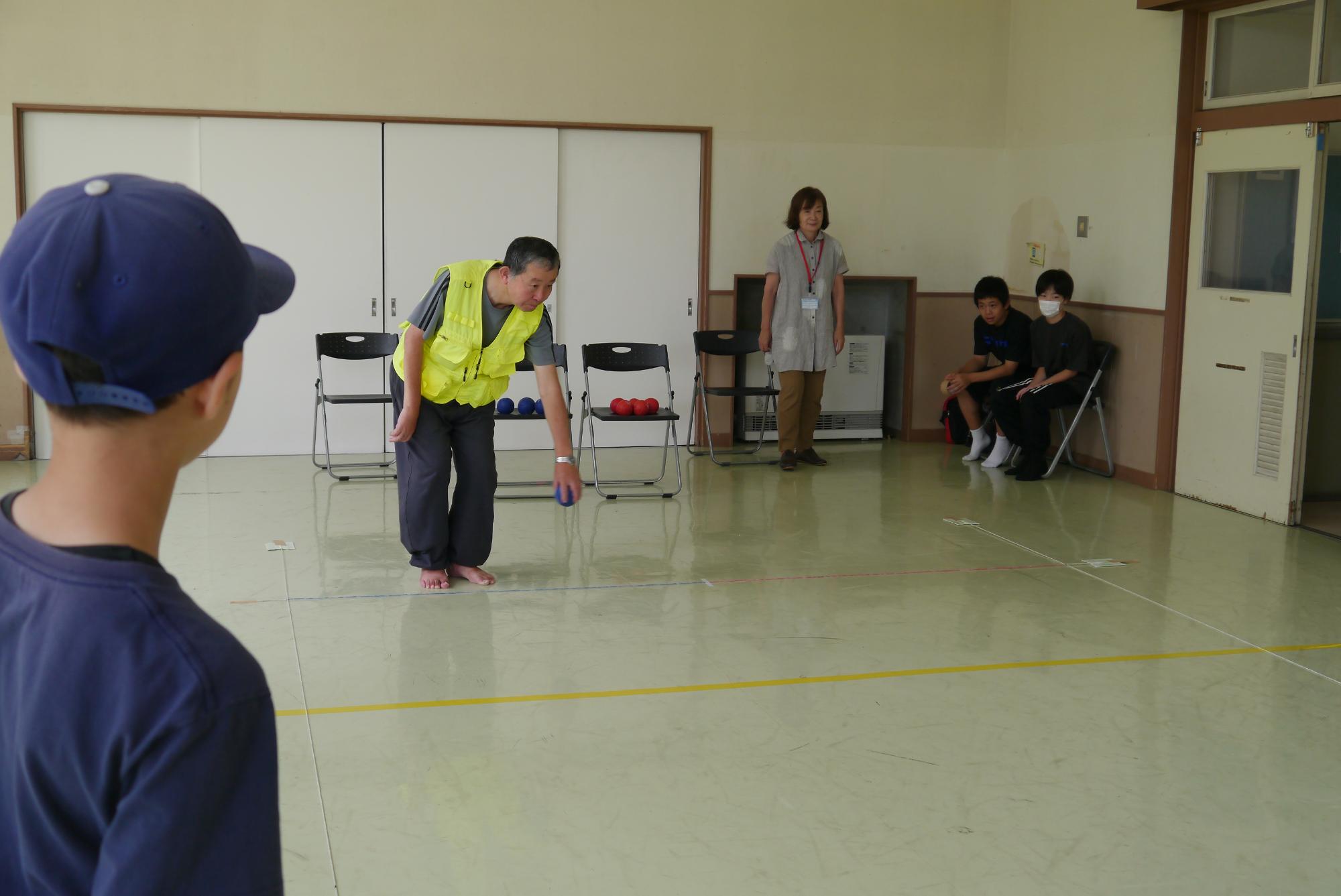 ボールを投げるボッチャの先生と見守る子どもたち