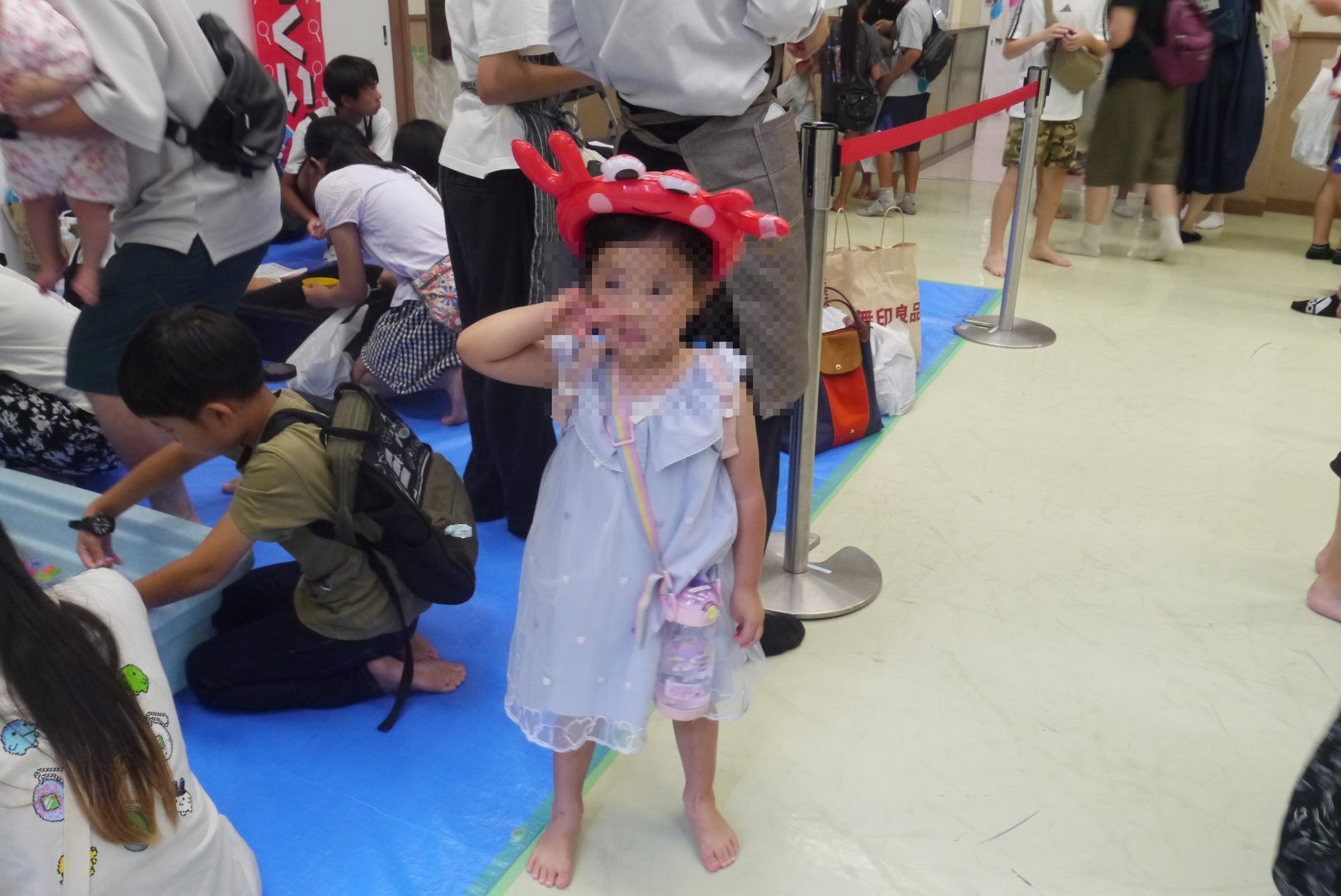 景品のカニのカチューシャをつける小さな女の子