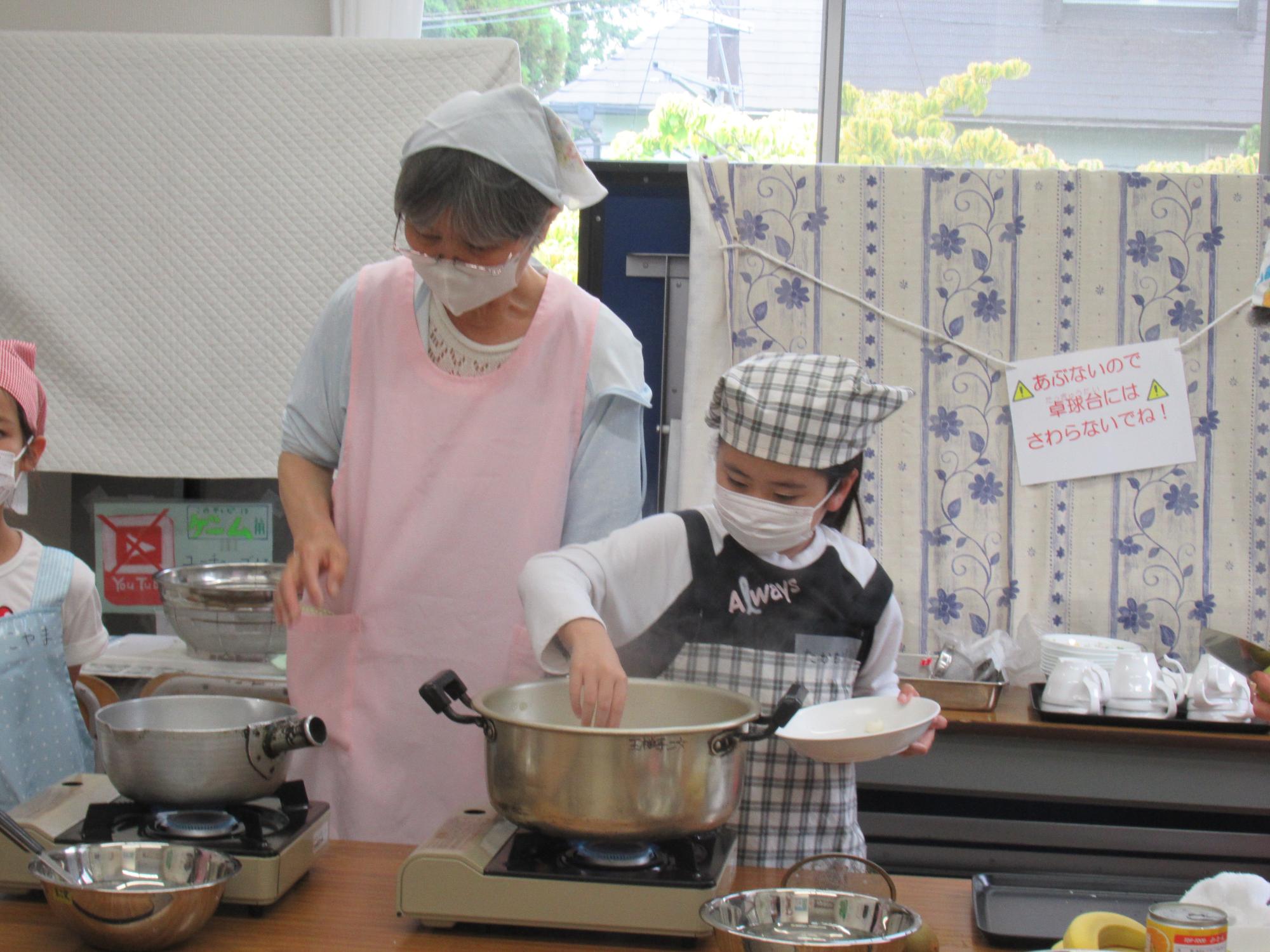 子どもが鍋で白玉だんごを茹でている写真