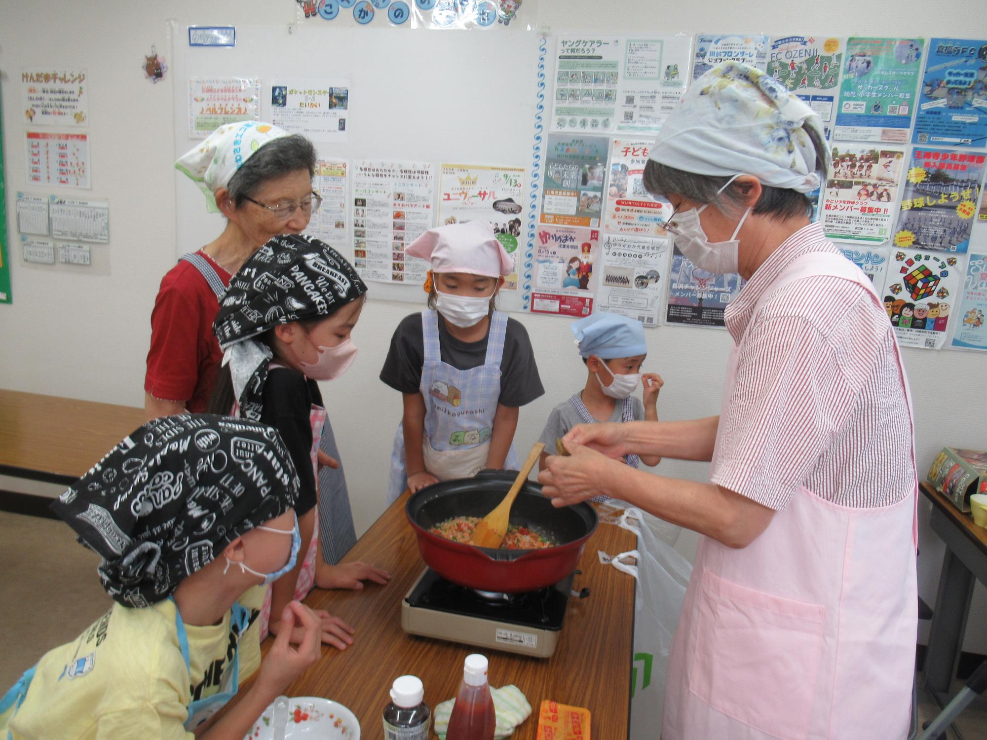 講師と子どもたちが鍋で野菜を煮込んでいる写真
