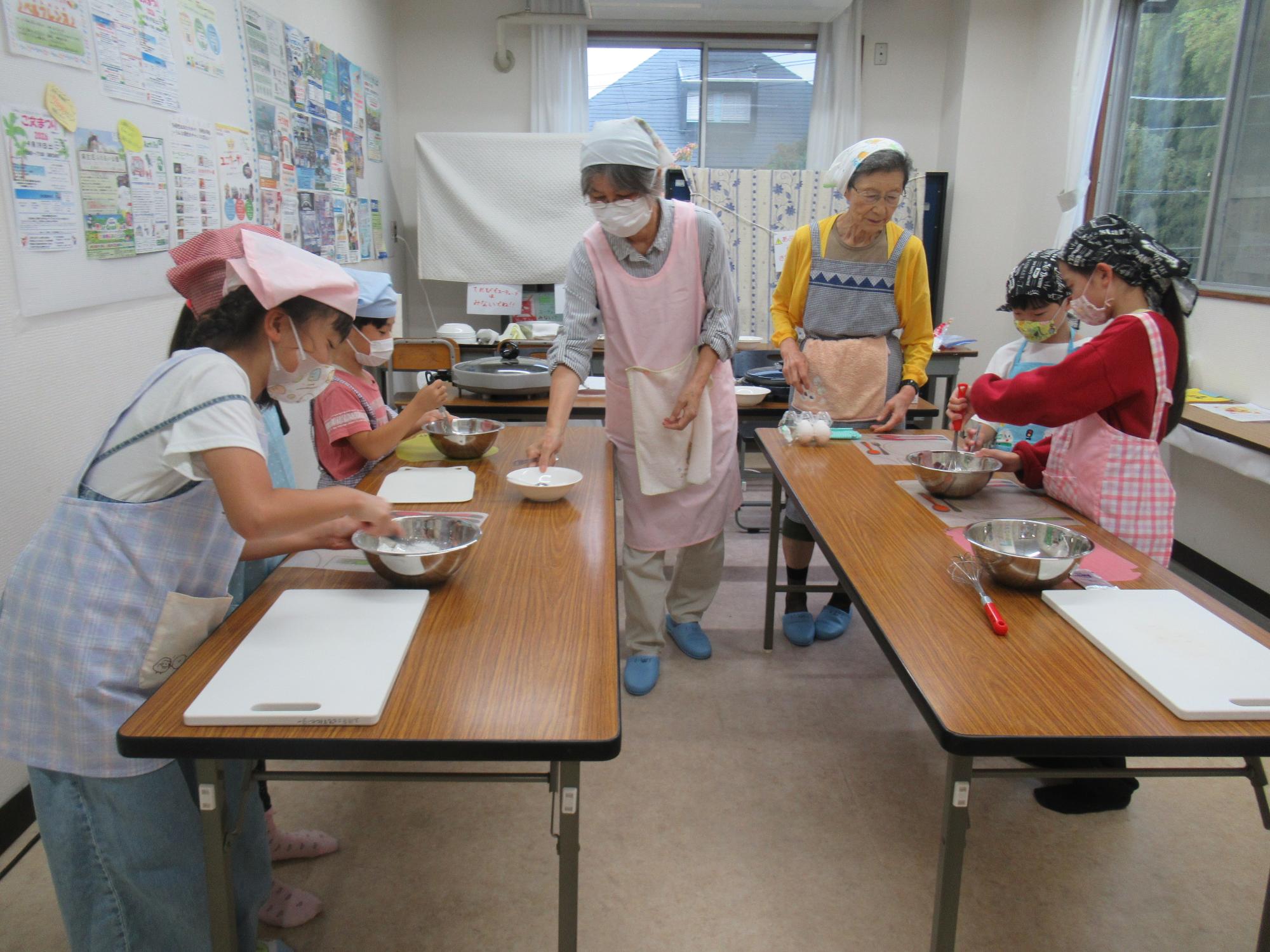 子ども達がケーキ―の粉をまぜている写真
